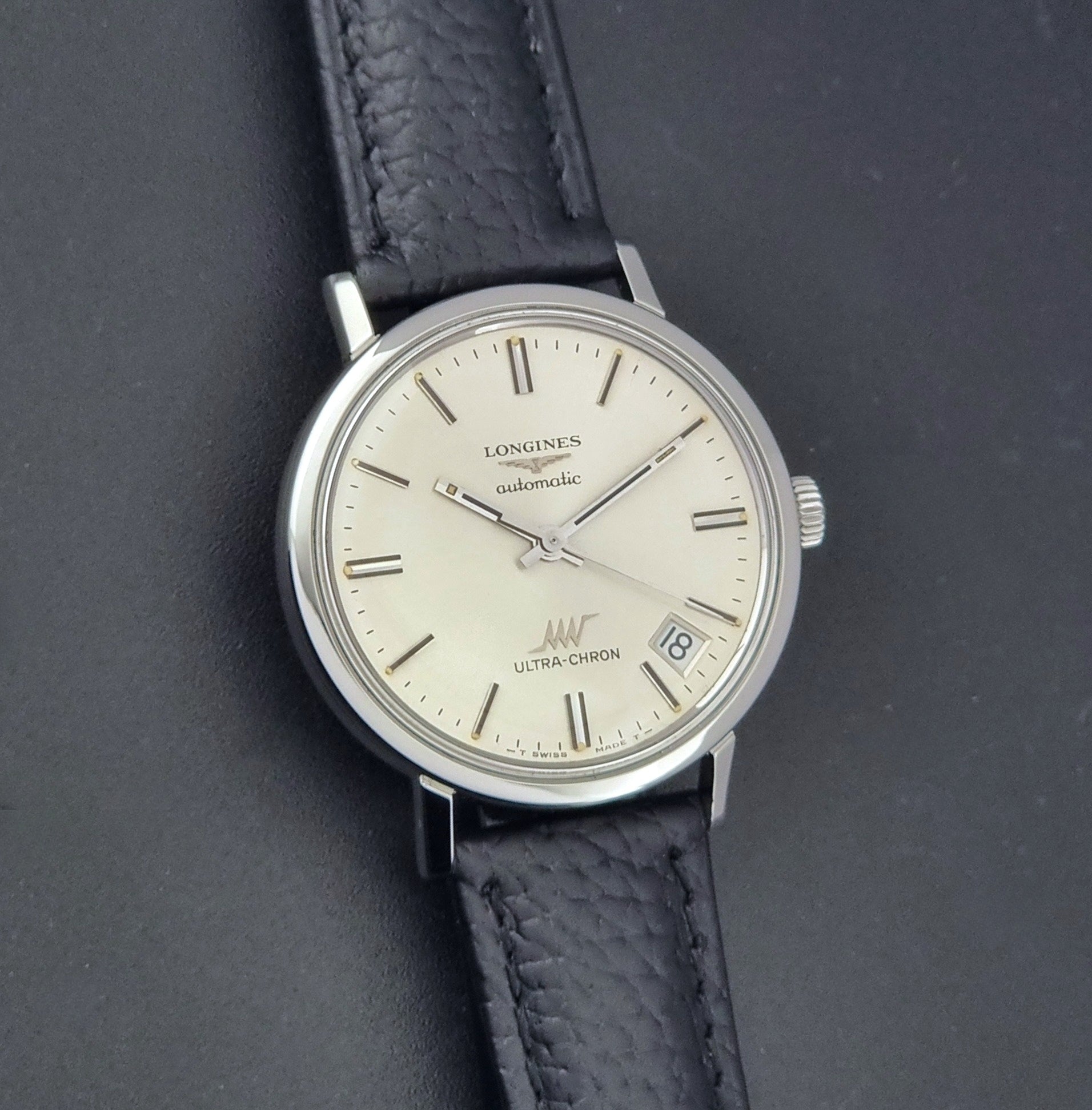 Vintage Longines ULTRA-CHRON 8383-1 with black leather strap and silver case on a dark gray background front view