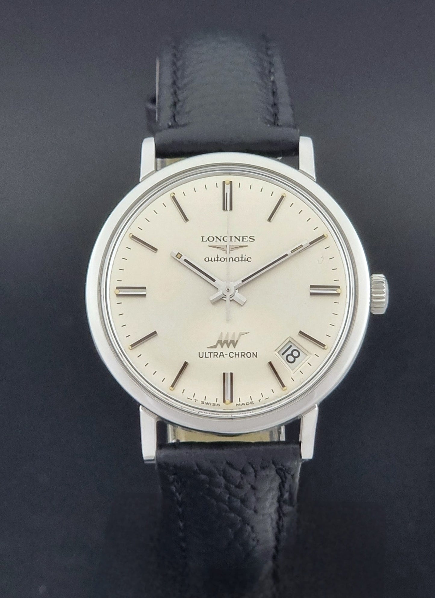 Vintage Longines ULTRA-CHRON 8383-1 with black leather strap and silver case on a dark gray background close dial view