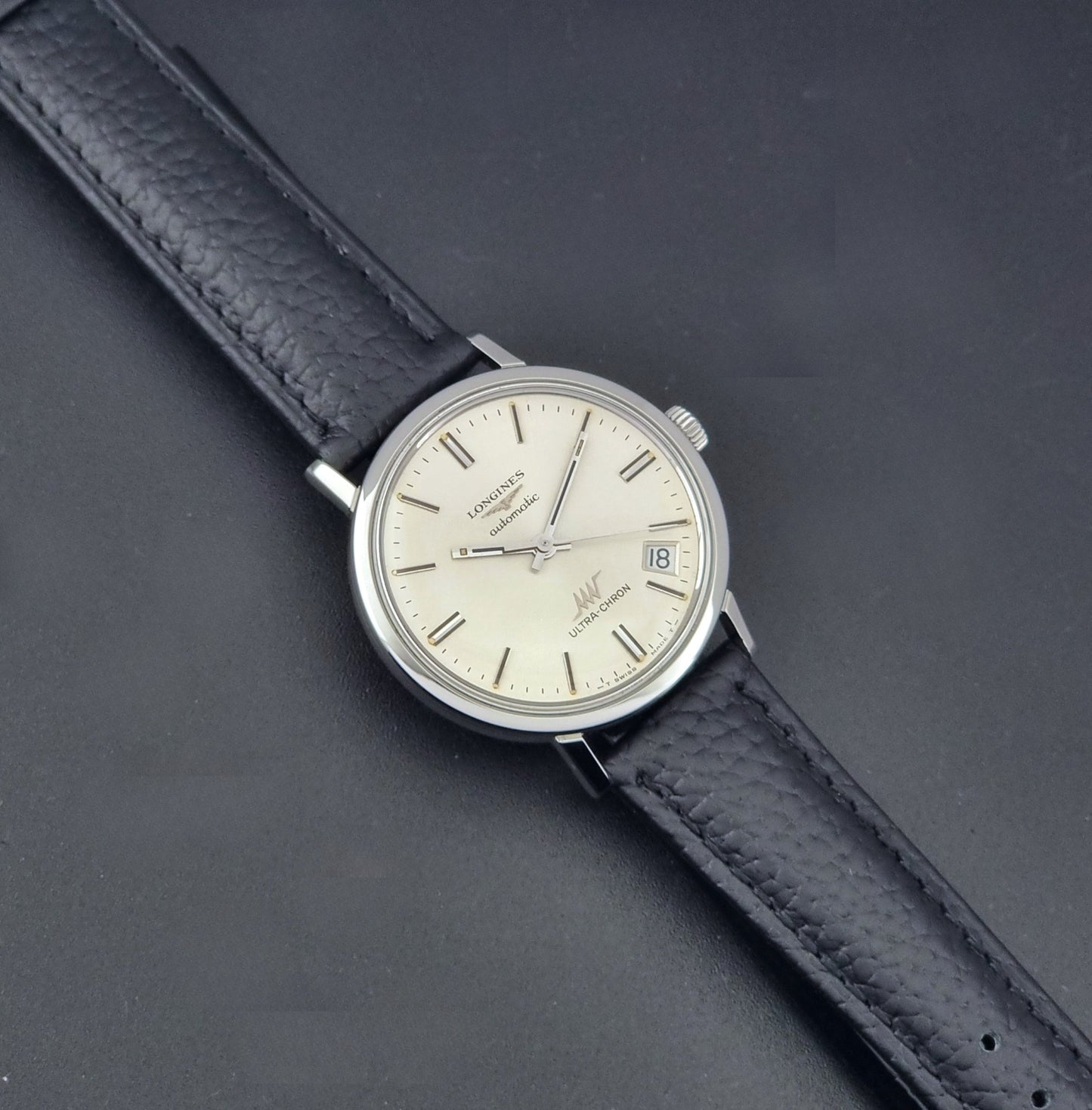 Vintage Longines ULTRA-CHRON 8383-1 with black leather strap and silver case on a dark gray background dial