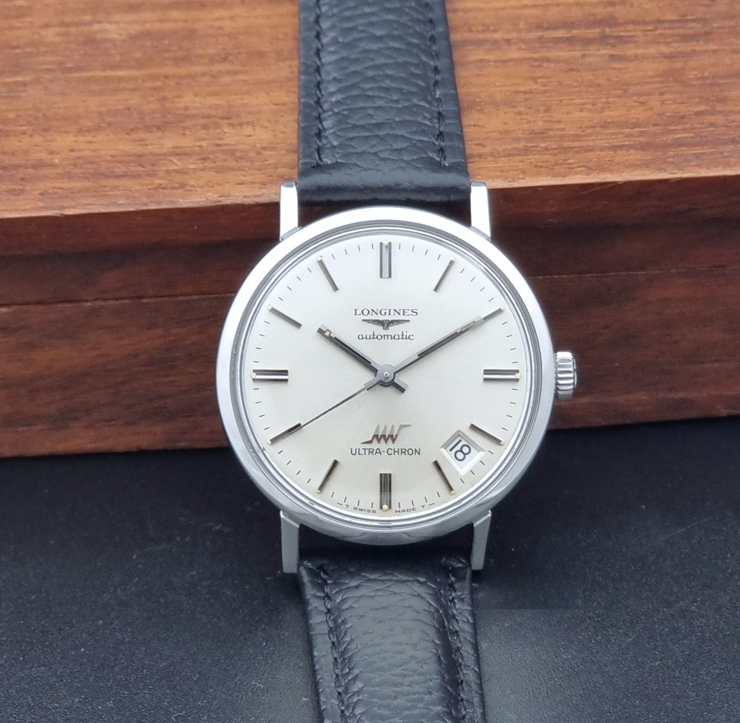 Vintage Longines ULTRA-CHRON 8383-1 with black leather strap and silver case on a dark gray background dial view