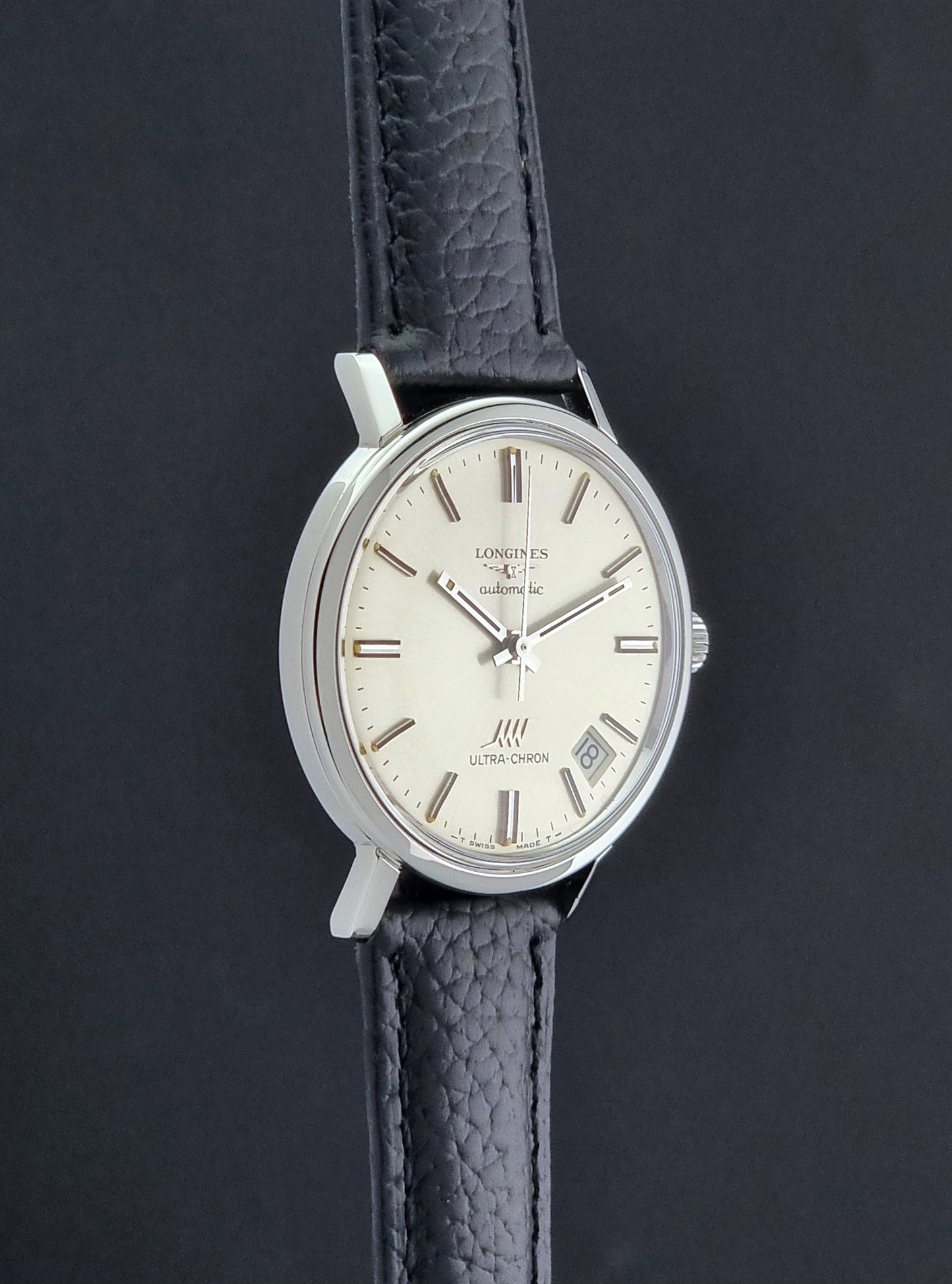 Vintage Longines ULTRA-CHRON 8383-1 with black leather strap and silver case on a dark gray background side profile view