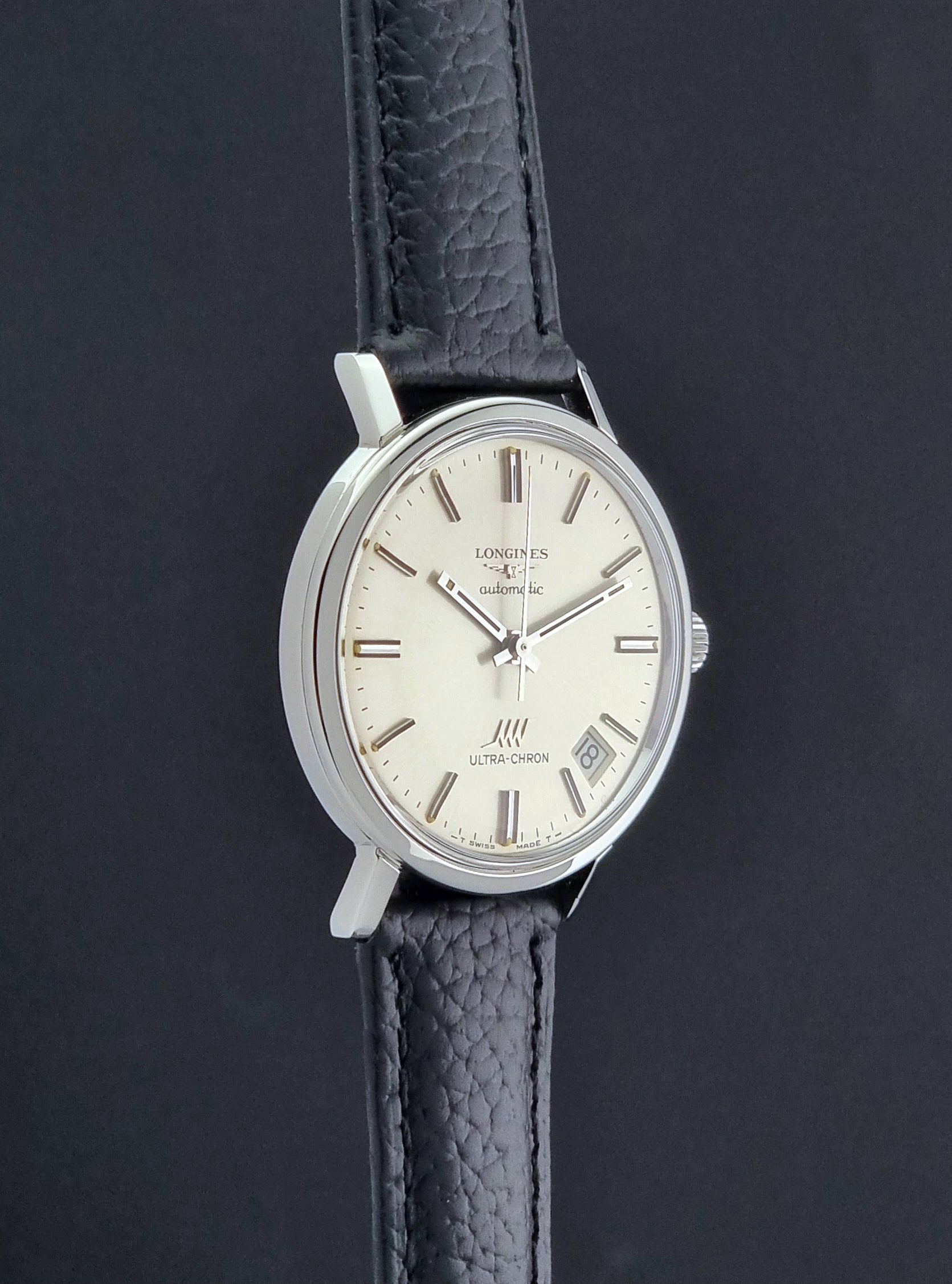 Vintage Longines ULTRA-CHRON 8383-1 with black leather strap and silver case on a dark gray background side profile view