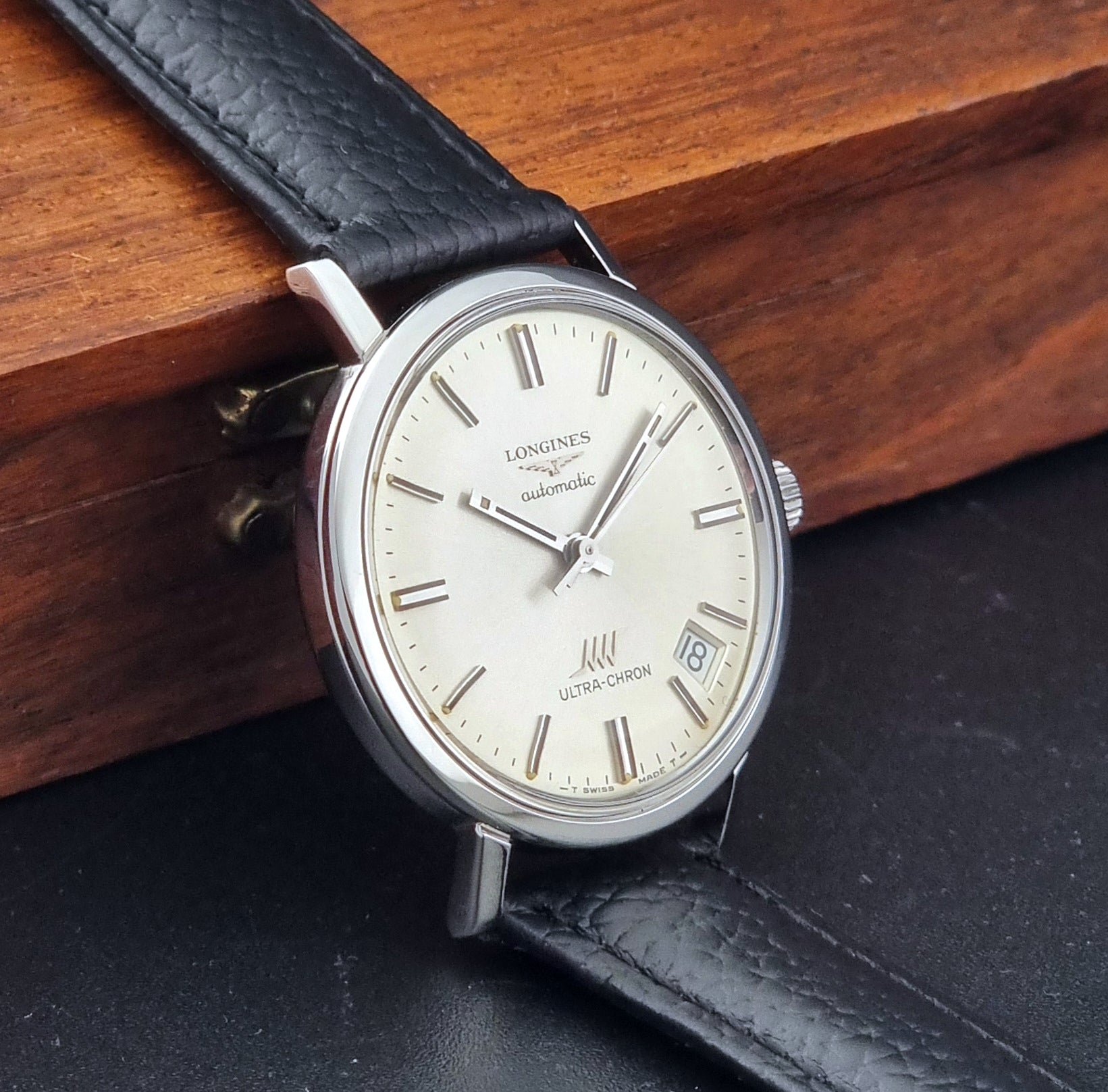Vintage Longines ULTRA-CHRON 8383-1 with black leather strap and silver case on a dark gray background side view