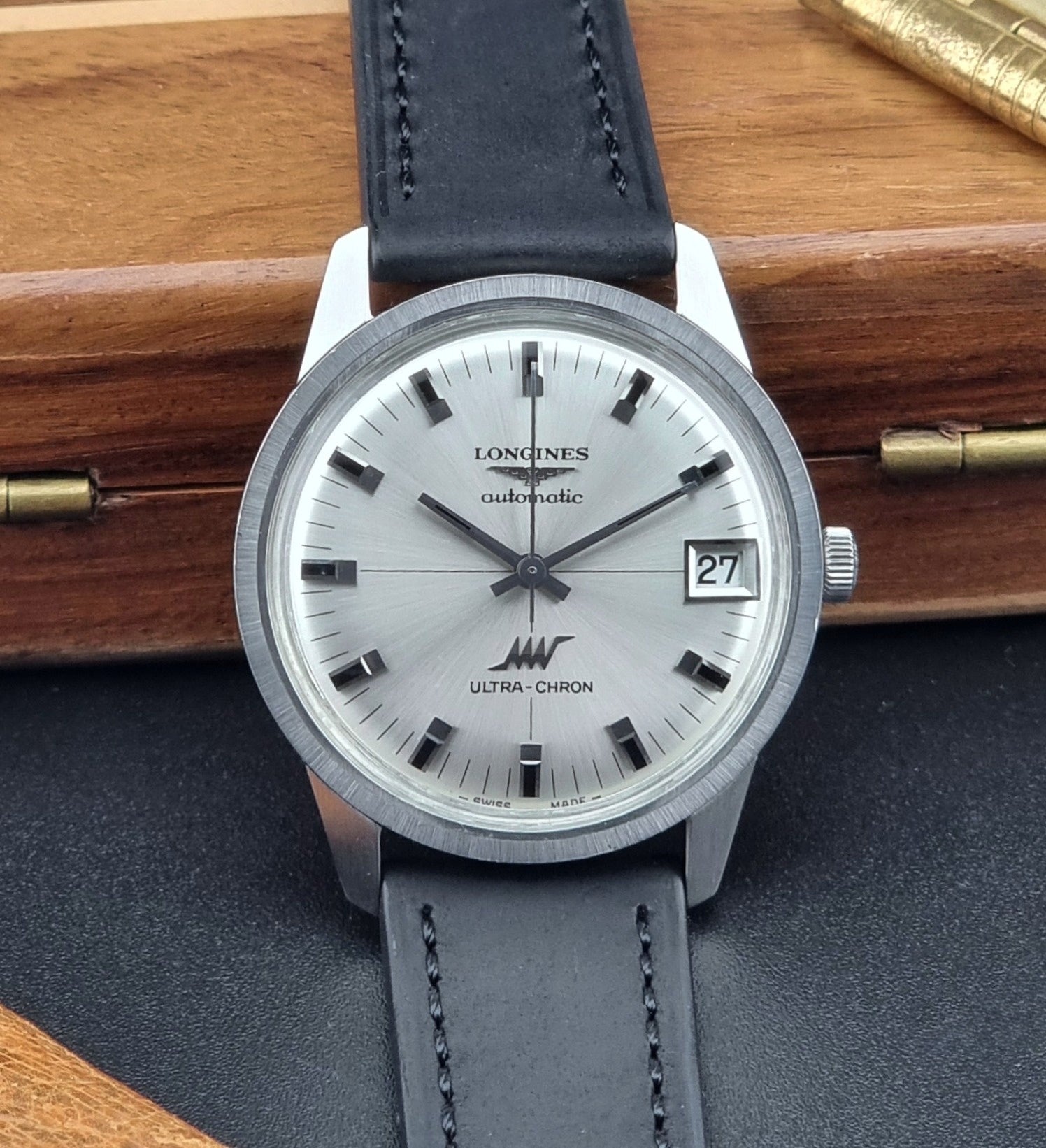 Longines watch with black leather strap on a wooden surface