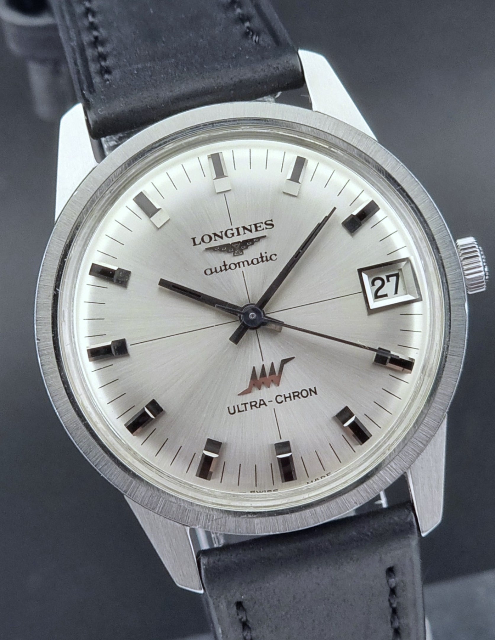 Longines Ultra-Chron watch with black leather strap on a dark background