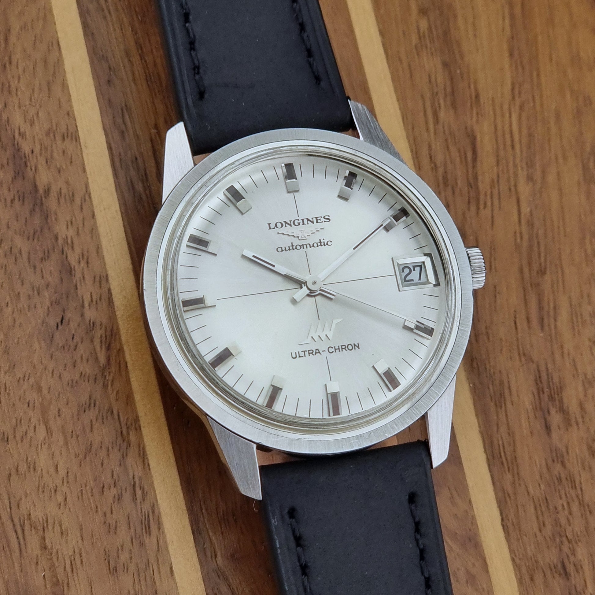 Longines watch with black leather strap on a wooden surface
