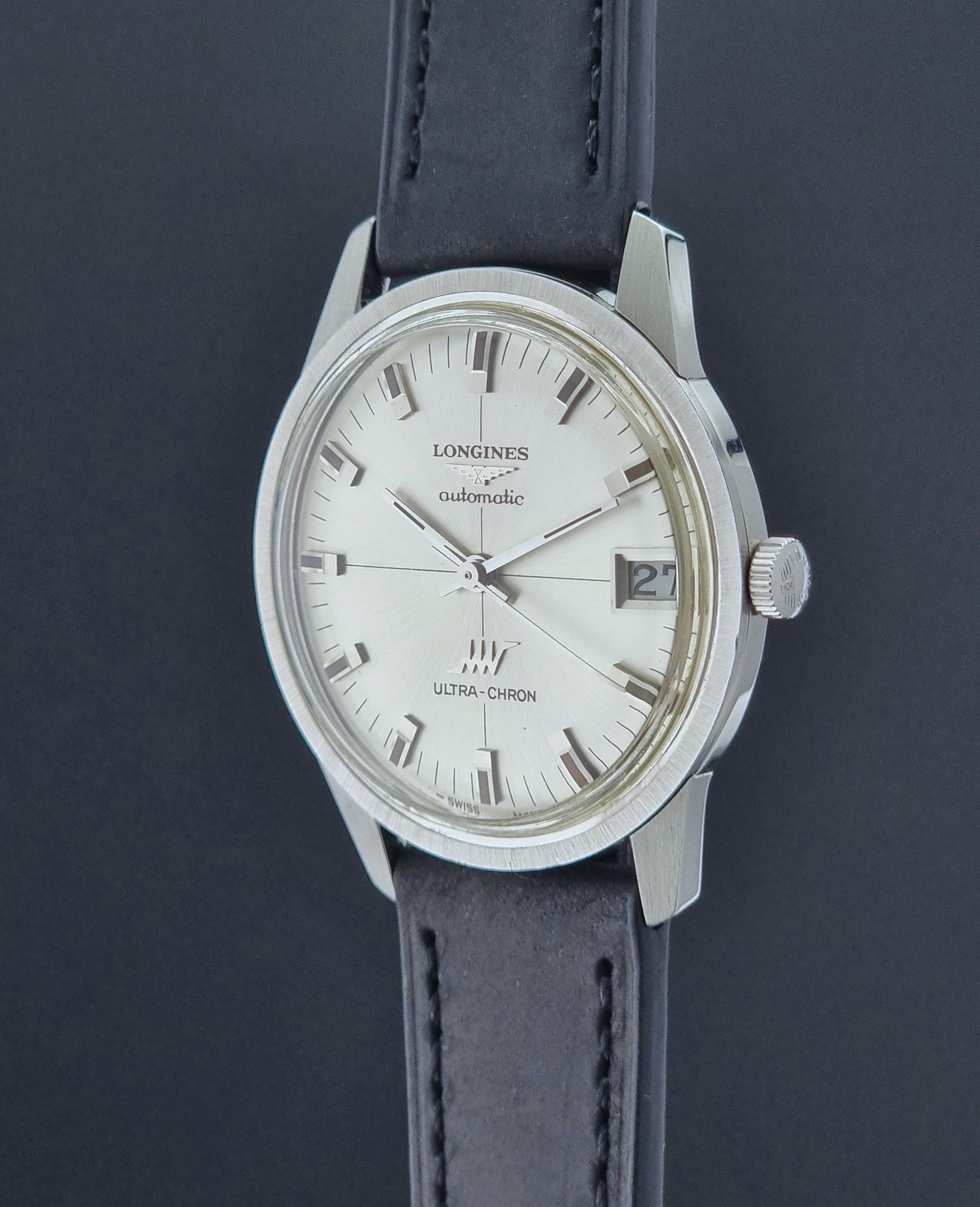 Longines watch with a silver dial and black leather strap on a dark background