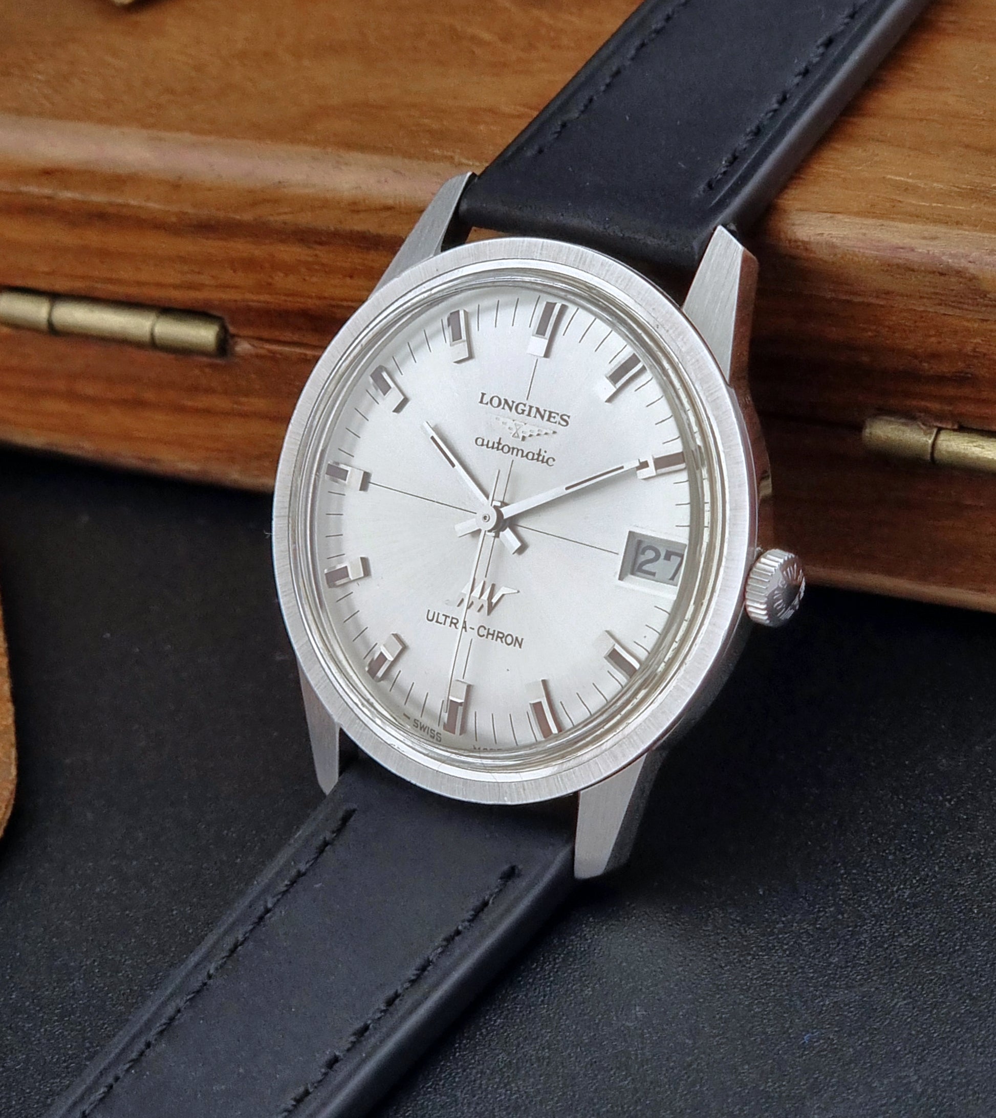 Longines watch with black leather strap on a wooden surface