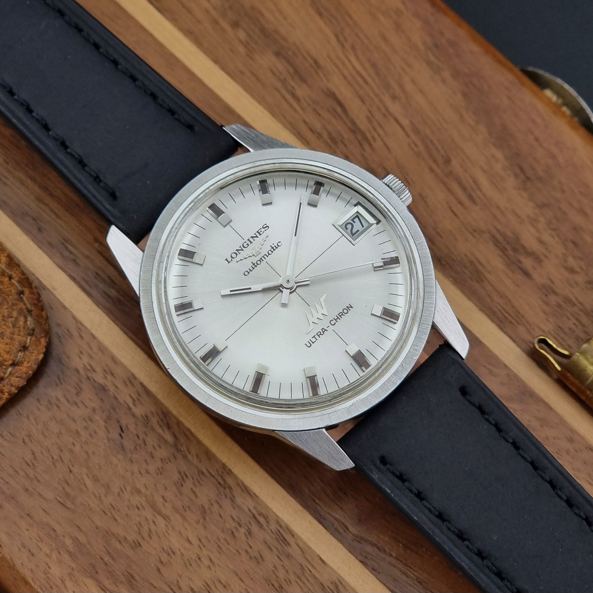 Longines watch with black leather strap on a wooden surface
