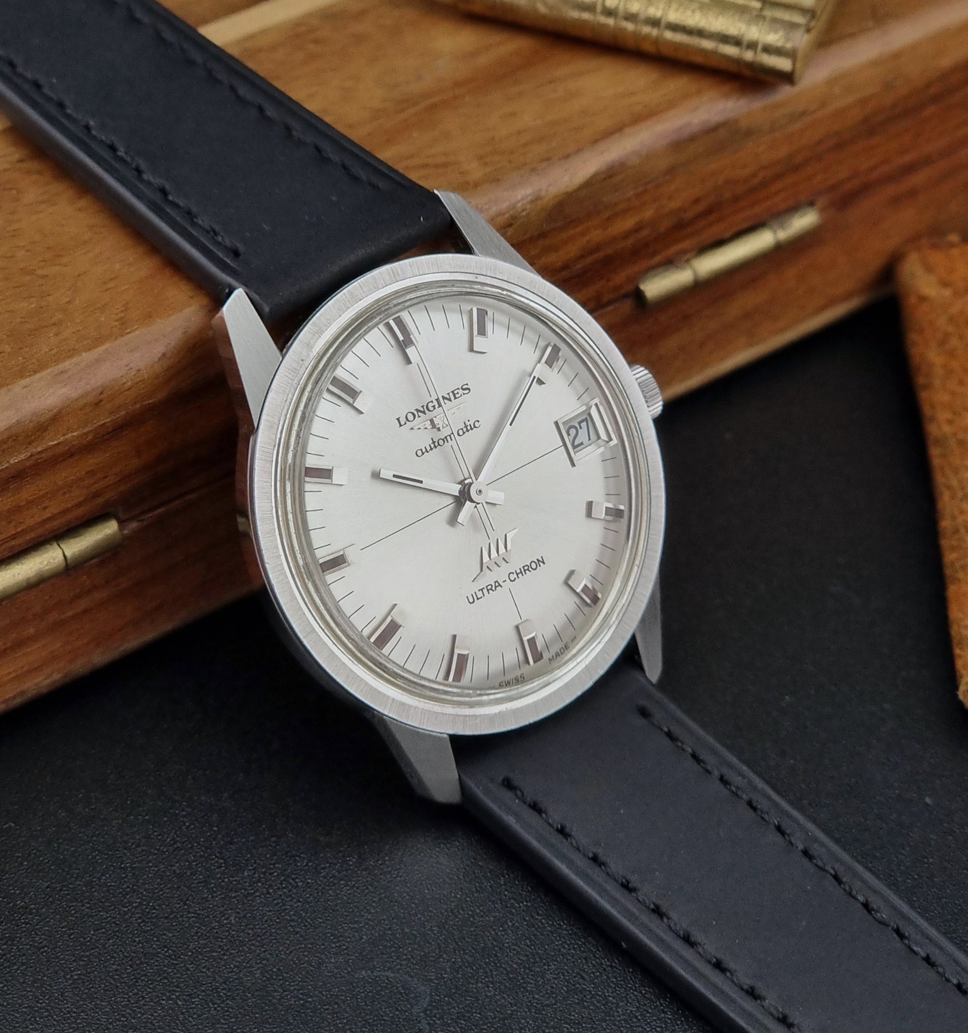 Longines watch with black leather strap on a wooden surface