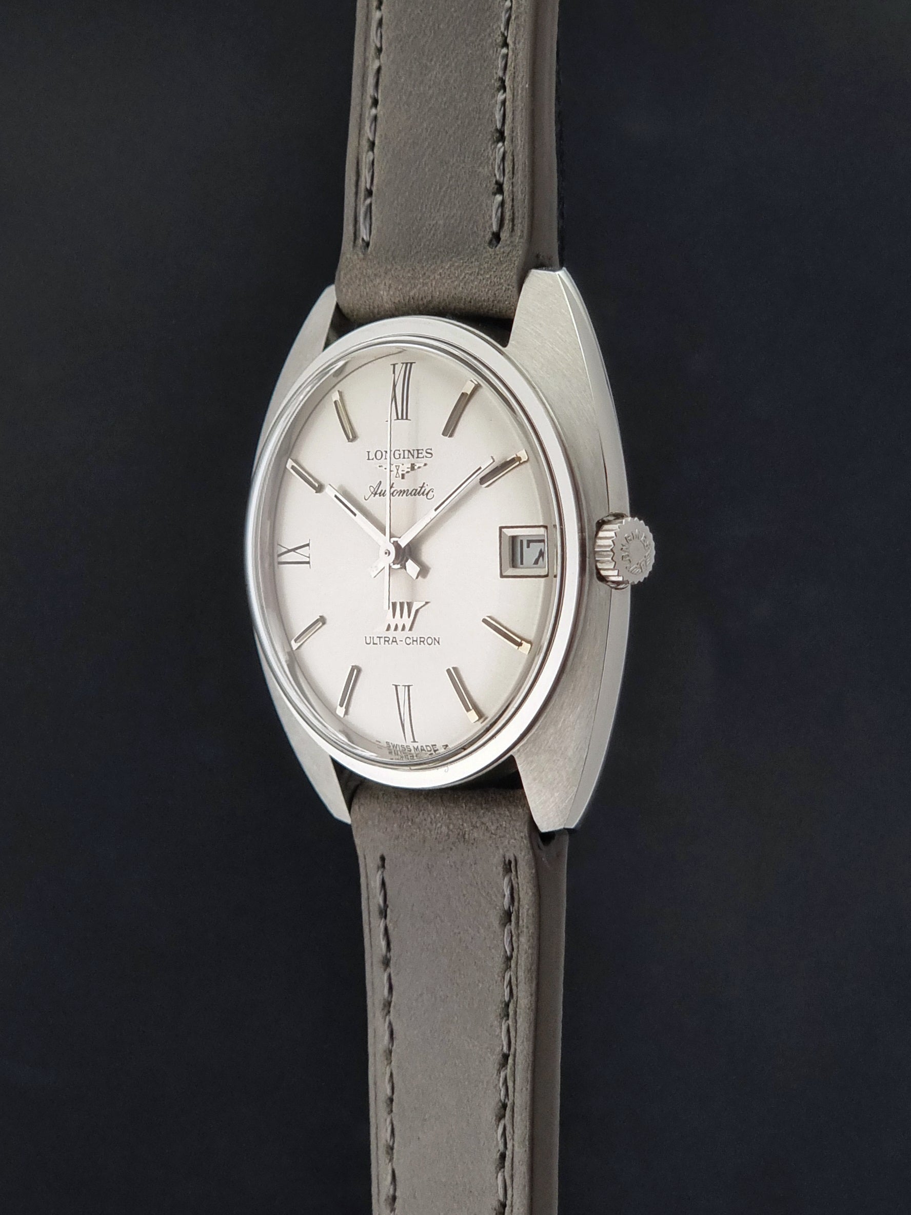Vintage Longines wristwatch ULTRA-CHRON 8317 with a grey leather strap on a dark background crown profile view