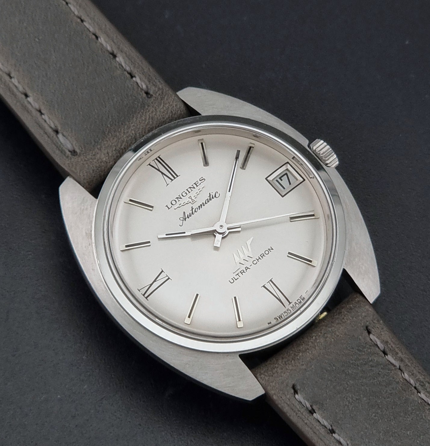 Vintage Longines wristwatch ULTRA-CHRON 8317 with a grey leather strap on a dark background close up dial view
