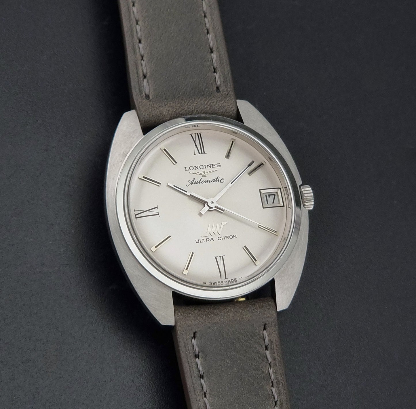 Vintage Longines wristwatch ULTRA-CHRON 8317 with a grey leather strap on a dark background front view