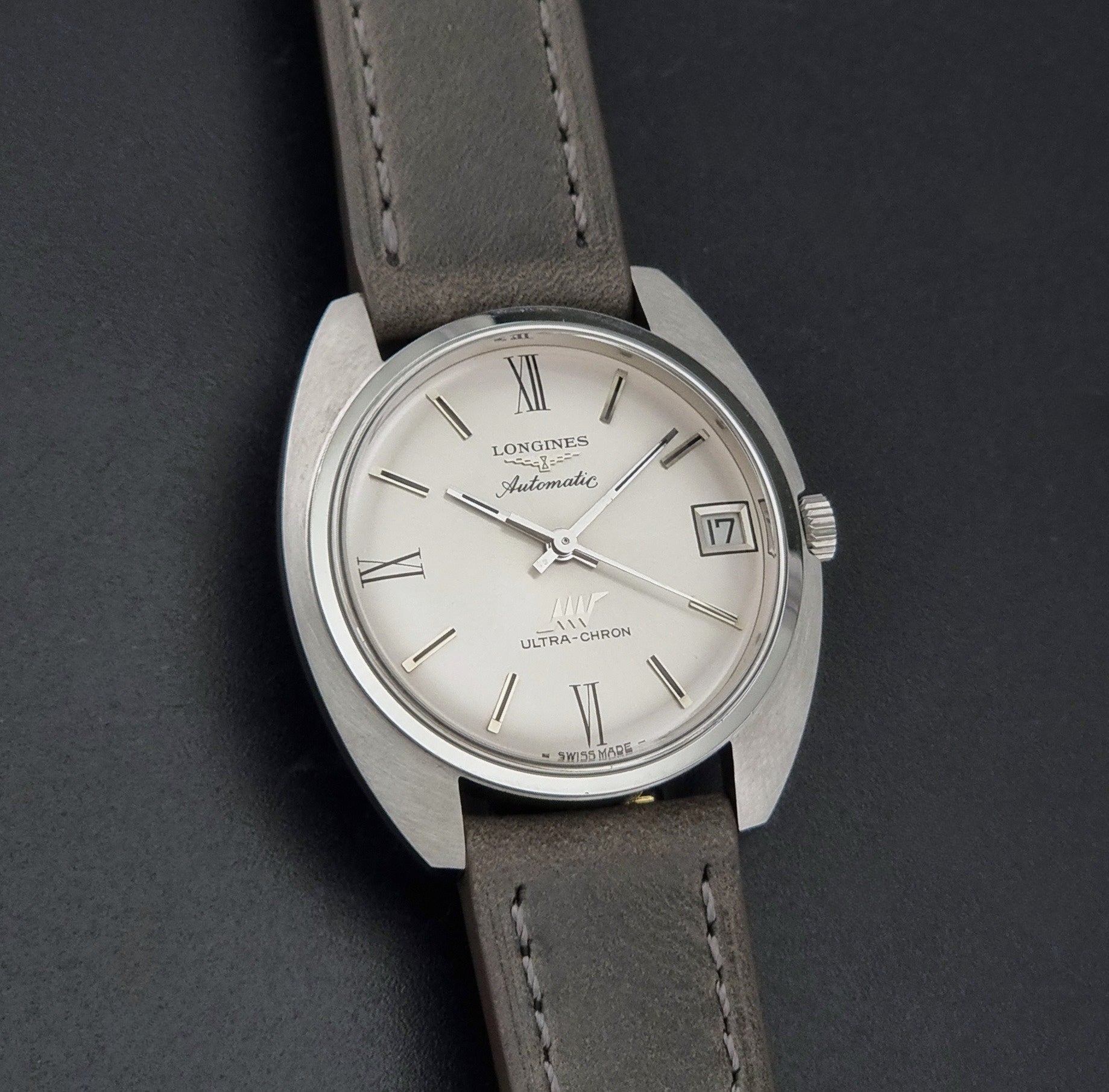 Vintage Longines wristwatch ULTRA-CHRON 8317 with a grey leather strap on a dark background front view