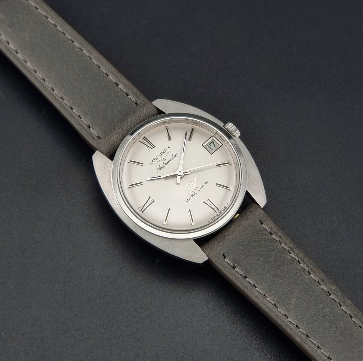Vintage Longines wristwatch ULTRA-CHRON 8317 with a grey leather strap on a dark background dial