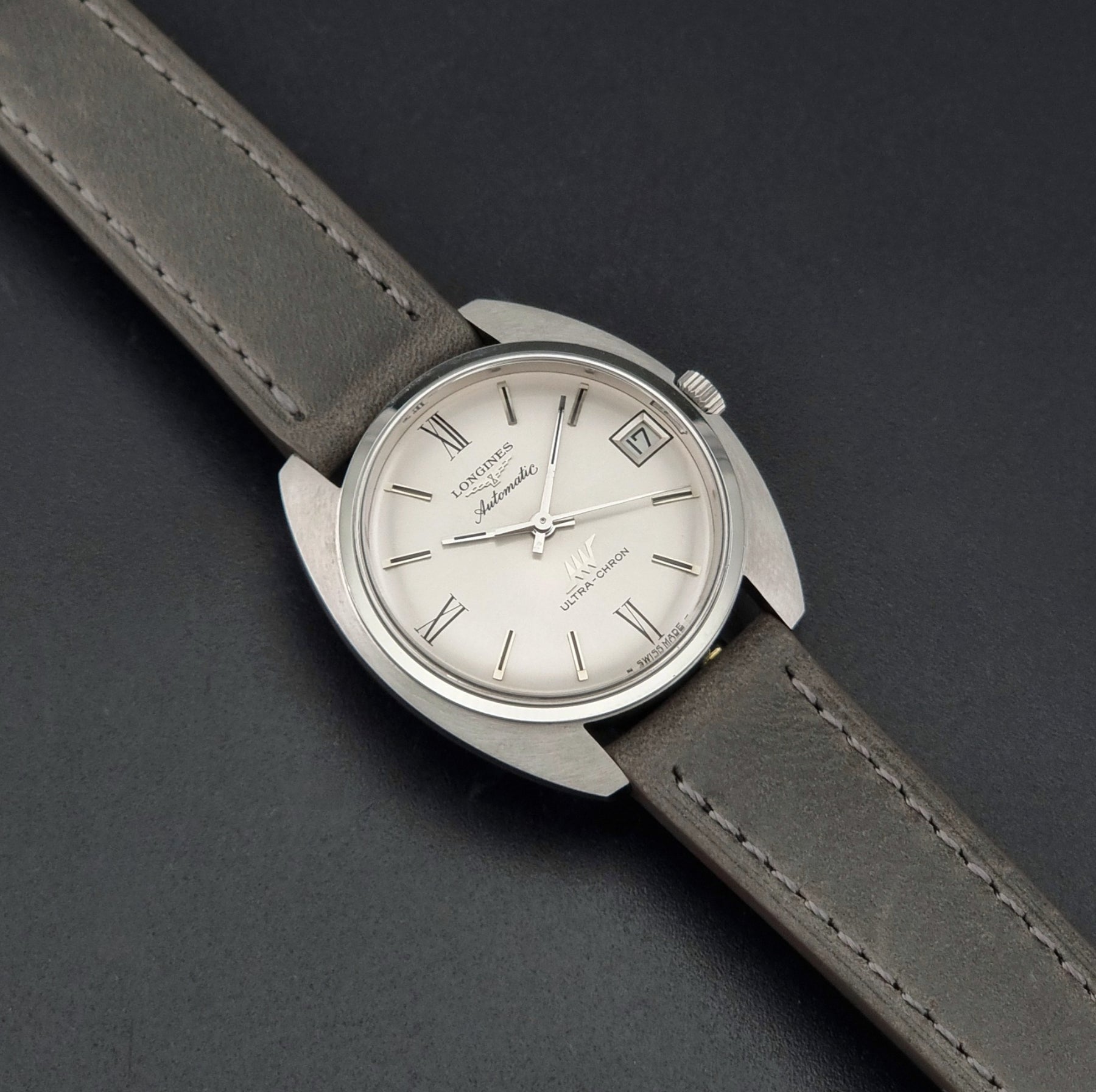 Vintage Longines wristwatch ULTRA-CHRON 8317 with a grey leather strap on a dark background dial