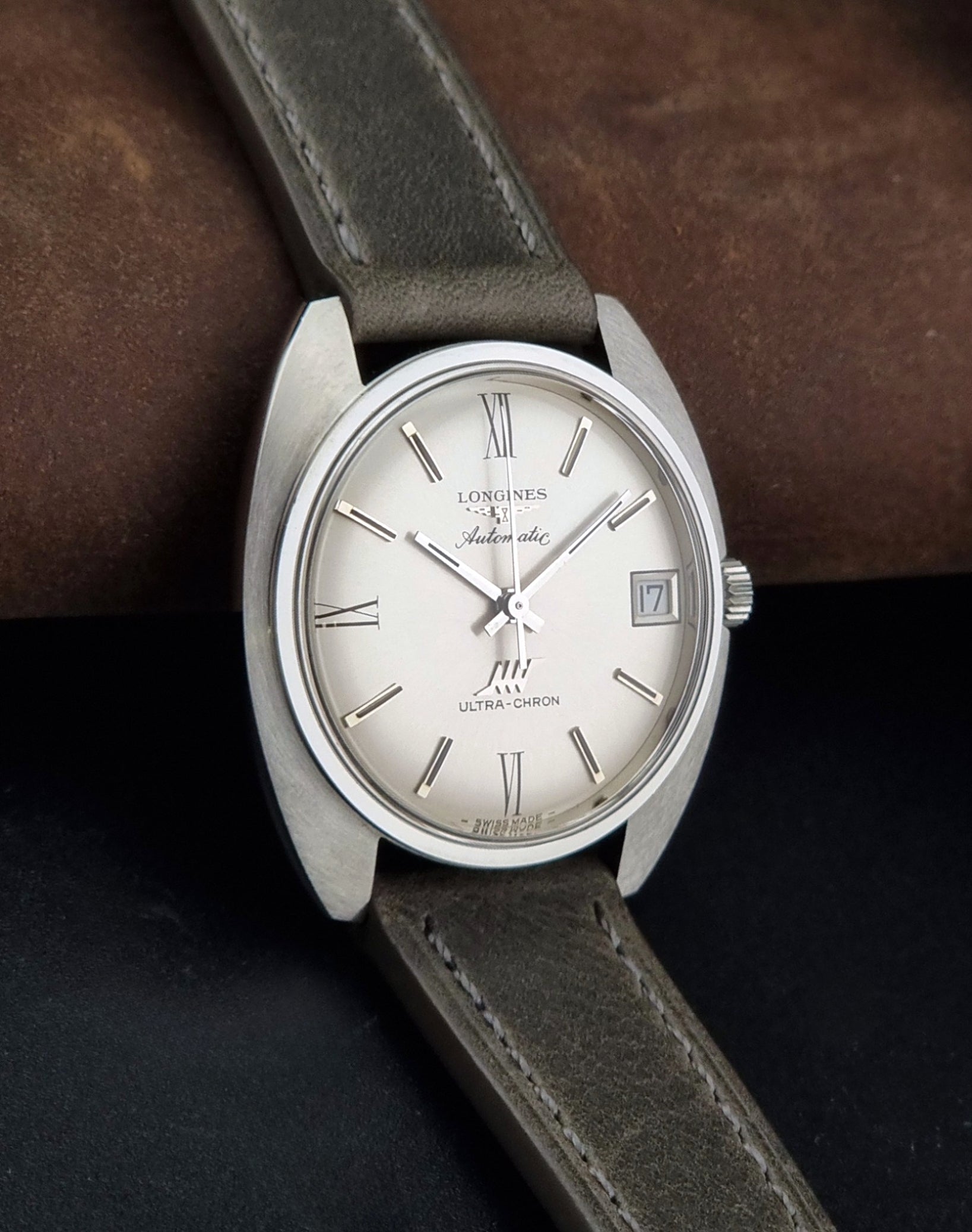 Vintage Longines wristwatch ULTRA-CHRON 8317 with a grey leather strap on a dark background side view