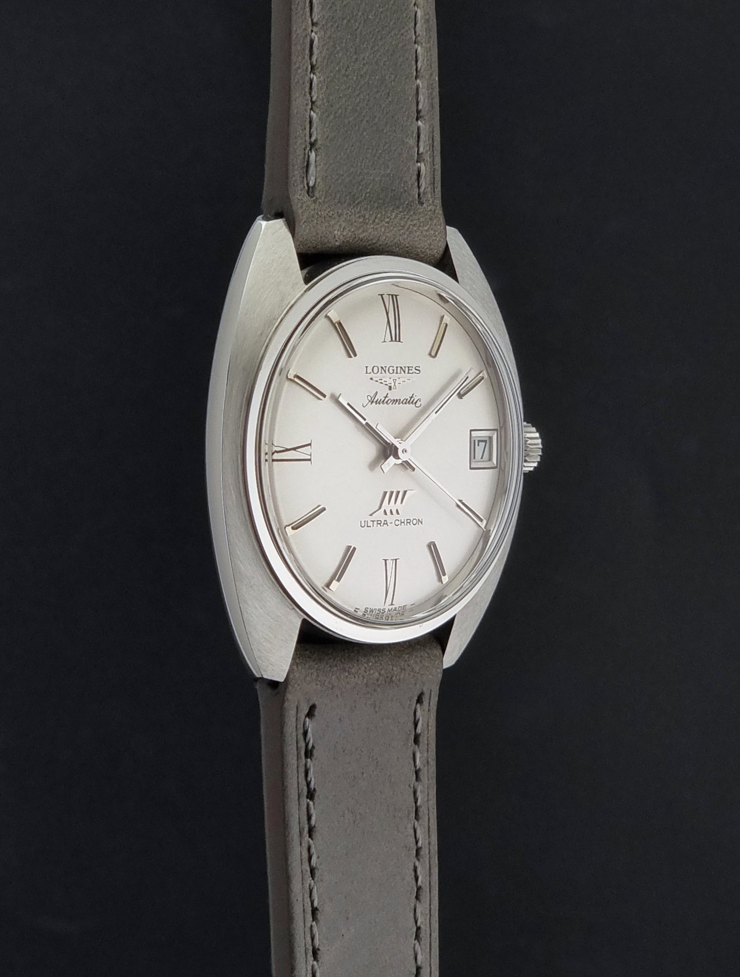 Vintage Longines wristwatch ULTRA-CHRON 8317 with a grey leather strap on a dark background side profile view