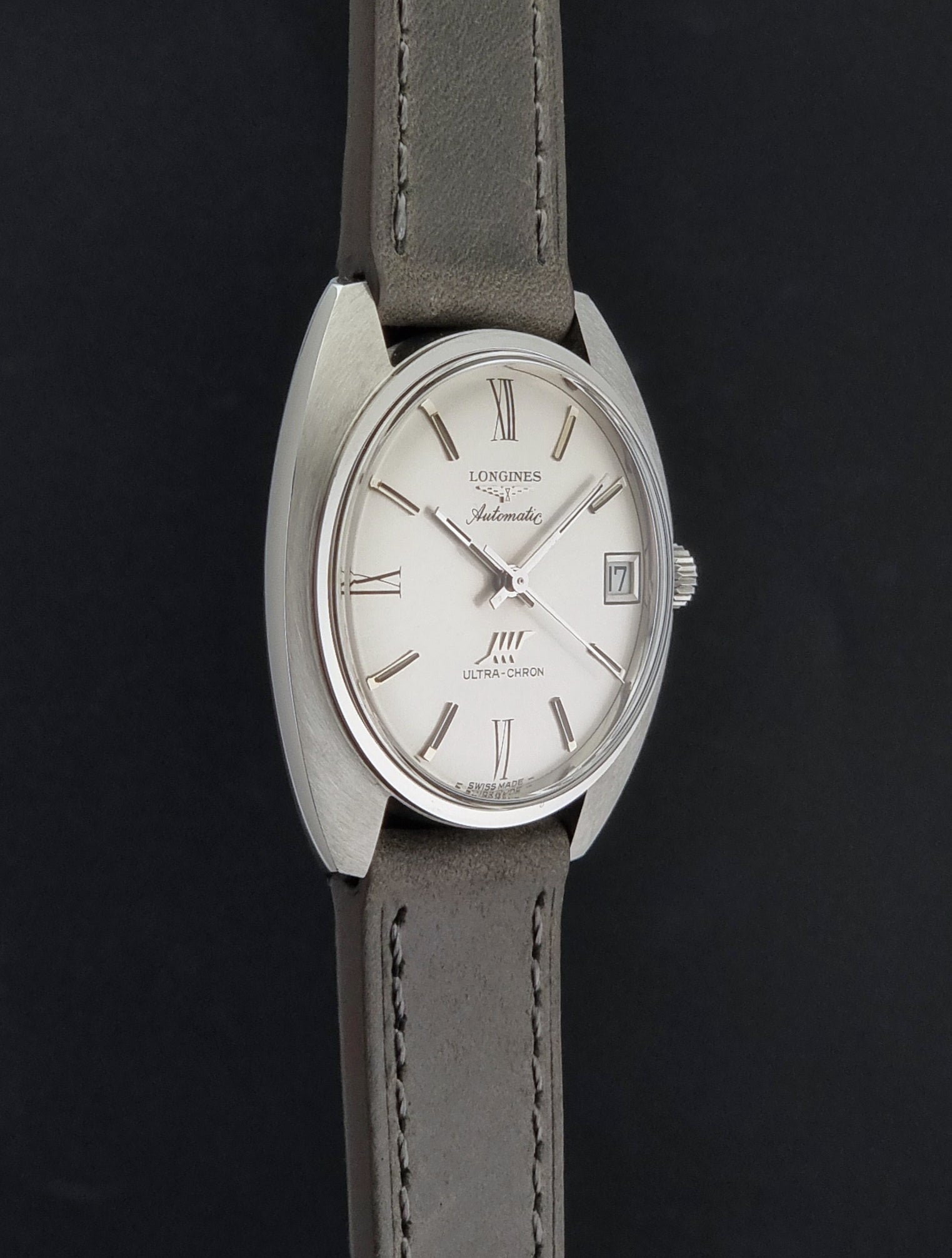 Vintage Longines wristwatch ULTRA-CHRON 8317 with a grey leather strap on a dark background side profile view