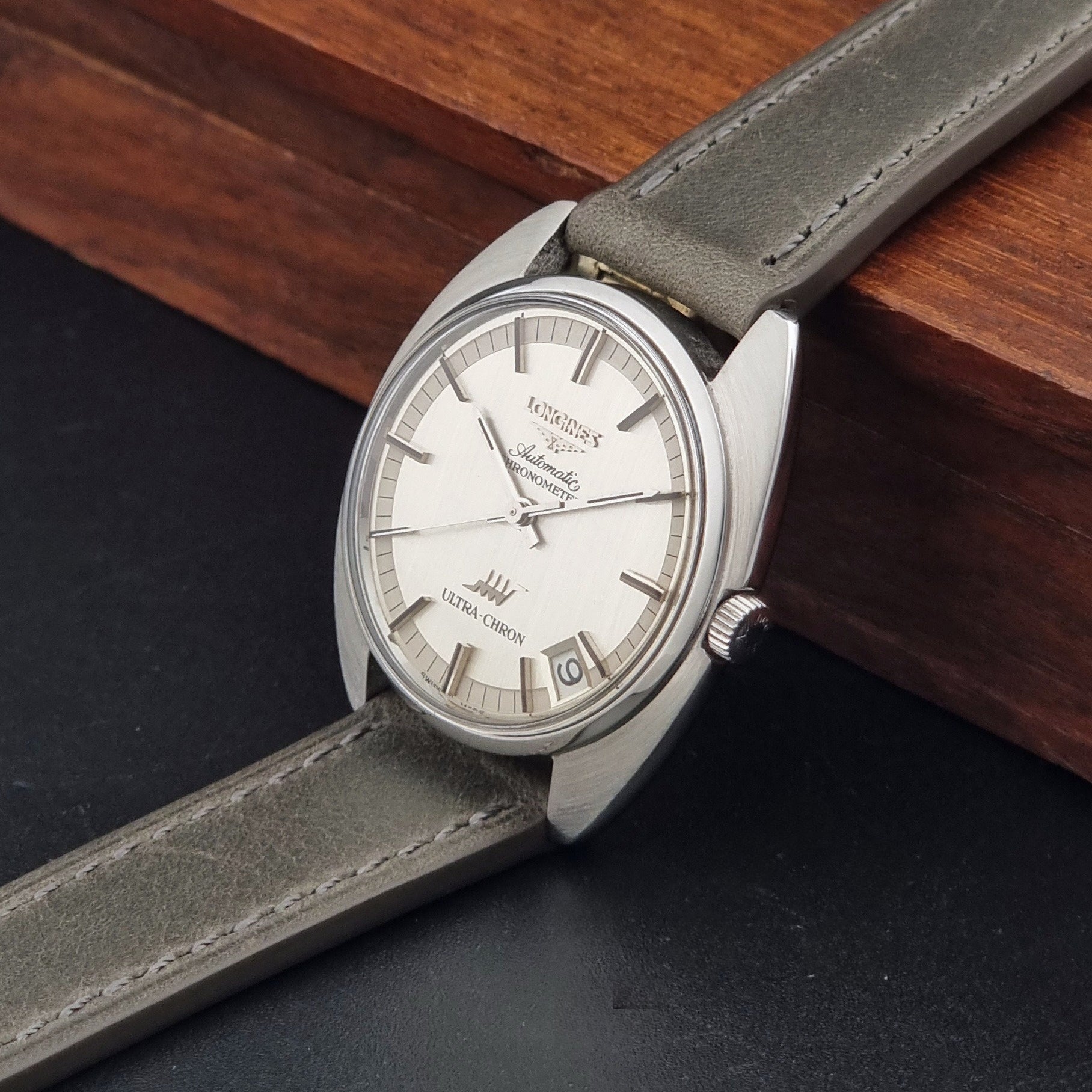 Vintage Longines ULTRA-CHRON 8353-1 watch with gray leather strap and silver case on a dark background crown view