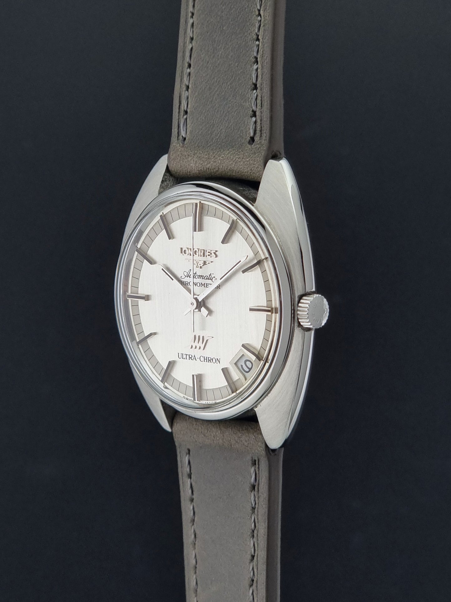 Vintage Longines ULTRA-CHRON 8353-1 watch with gray leather strap and silver case on a dark background crown profile view
