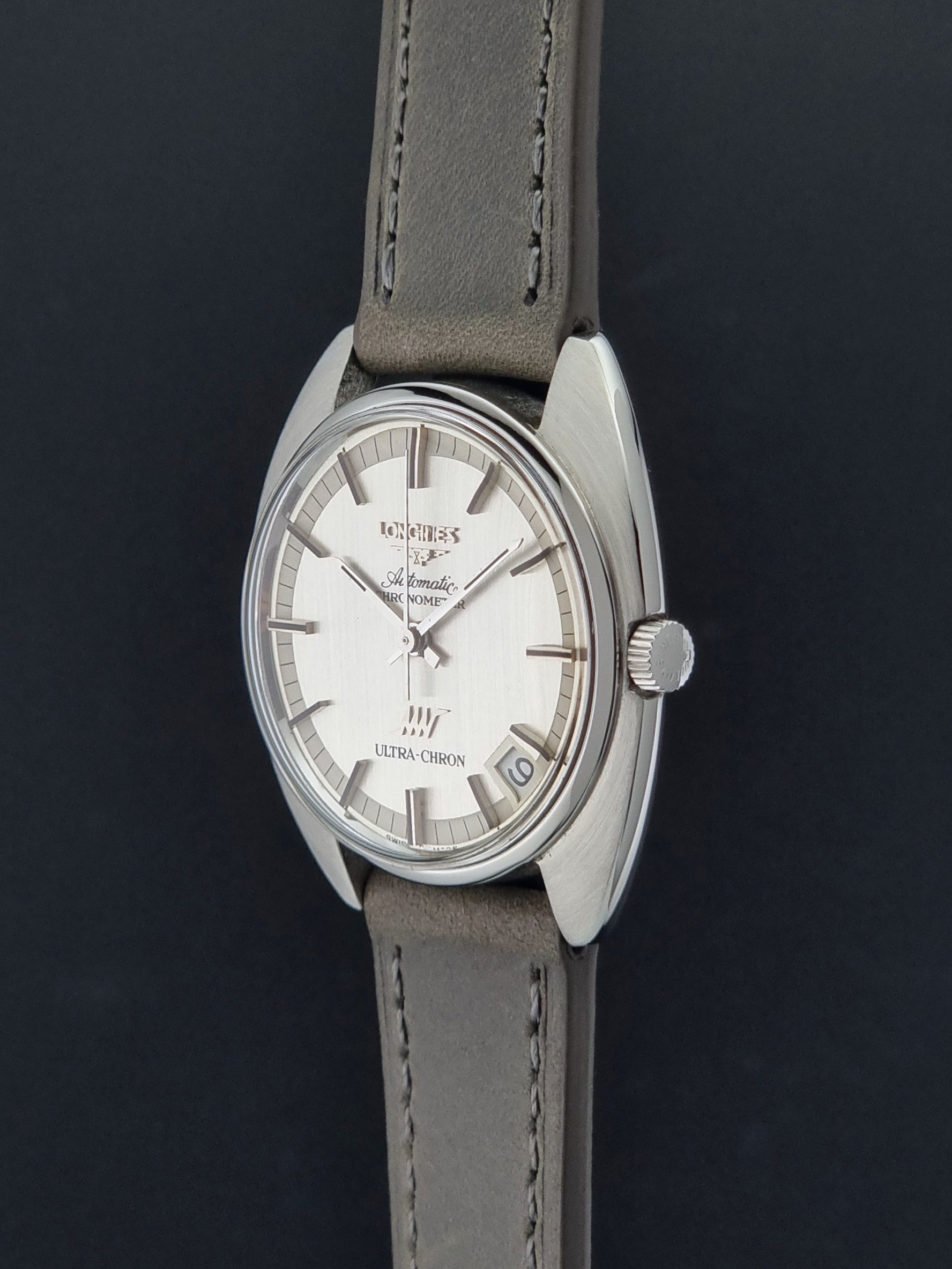 Vintage Longines ULTRA-CHRON 8353-1 watch with gray leather strap and silver case on a dark background crown profile view