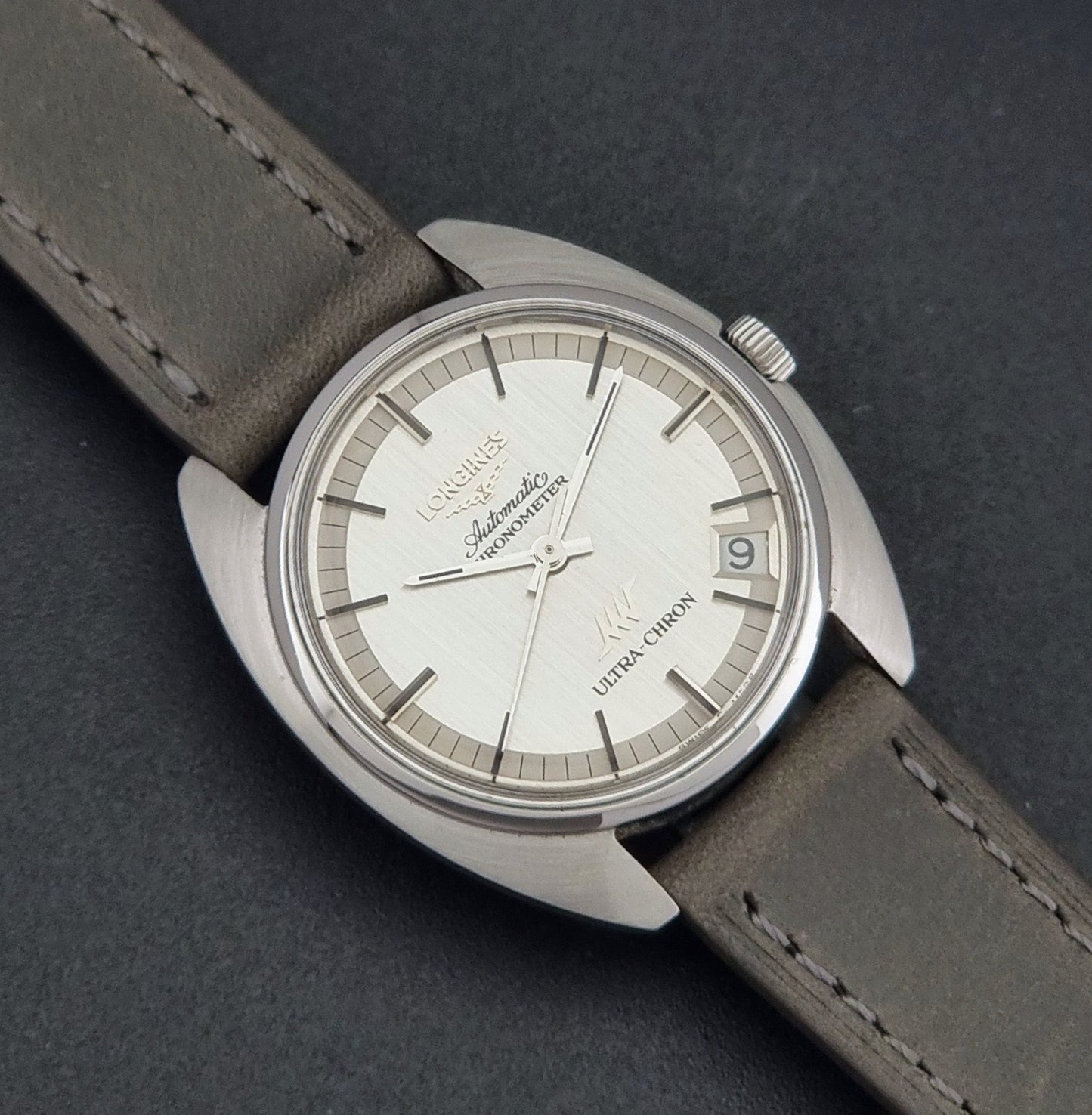 Vintage Longines ULTRA-CHRON 8353-1 watch with gray leather strap and silver case on a dark background close up dial view