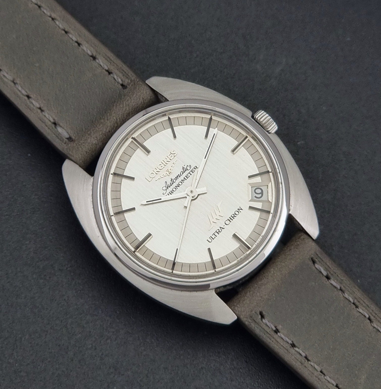 Vintage Longines ULTRA-CHRON 8353-1 watch with gray leather strap and silver case on a dark background close up dial view