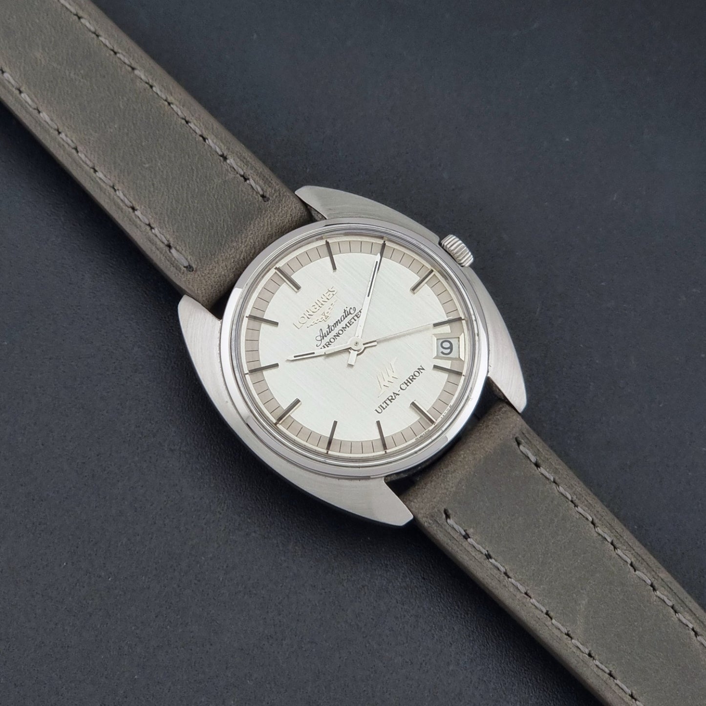 Vintage Longines ULTRA-CHRON 8353-1 watch with gray leather strap and silver case on a dark background dial 