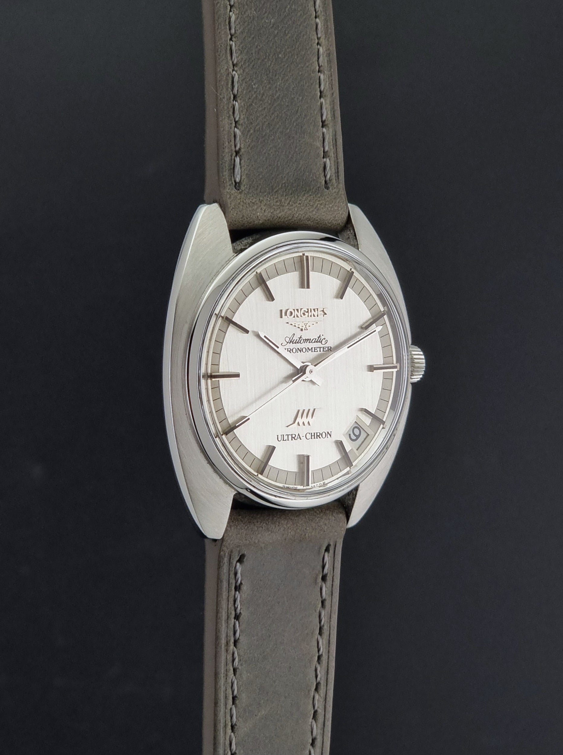 Vintage Longines ULTRA-CHRON 8353-1 watch with gray leather strap and silver case on a dark background side profiel view