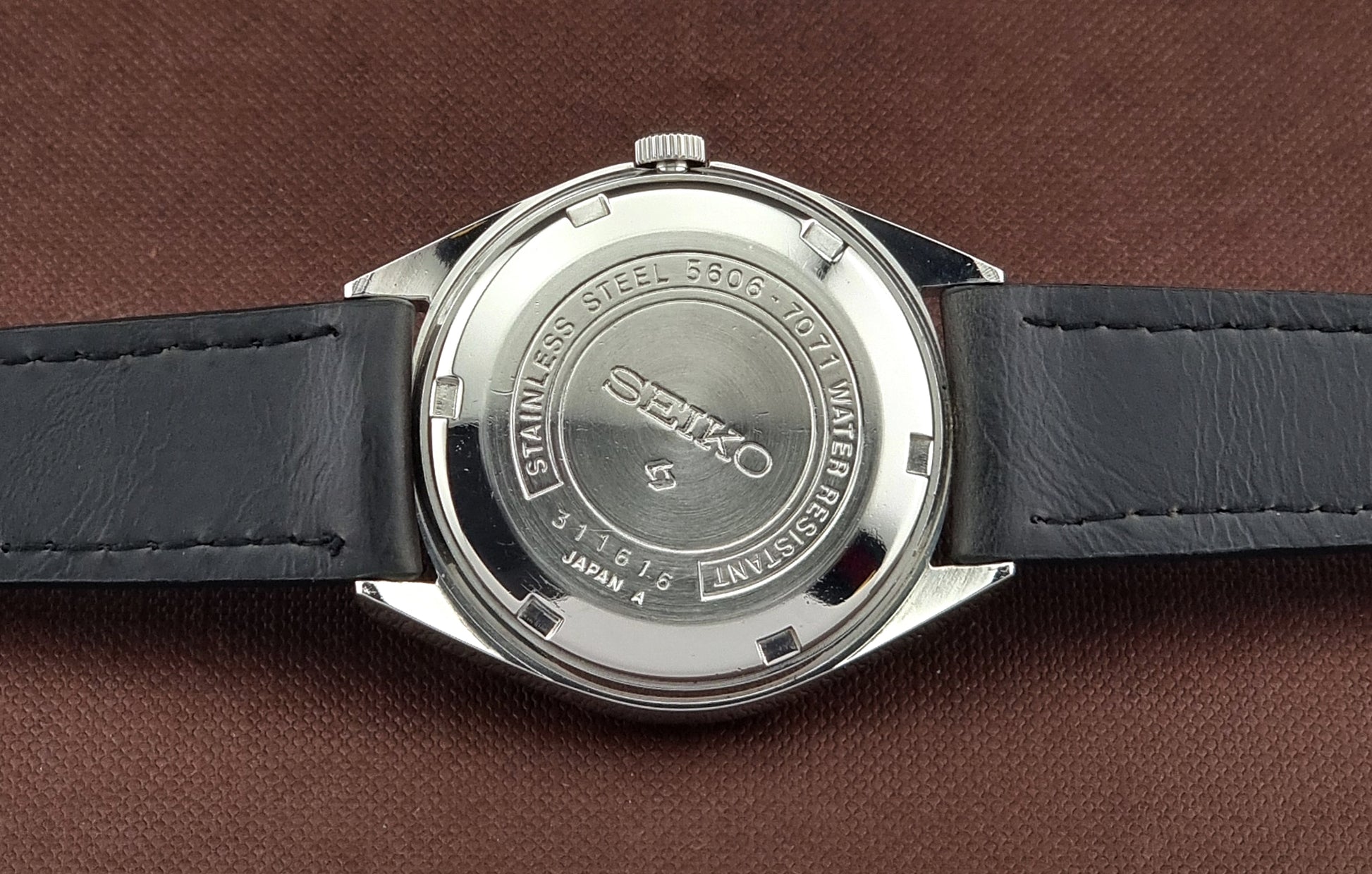 Back view of a Seiko watch on a brown leather background