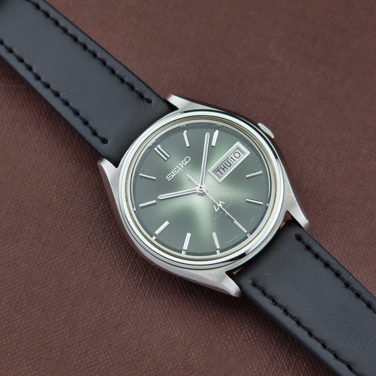 Seiko watch with black leather strap on a brown background