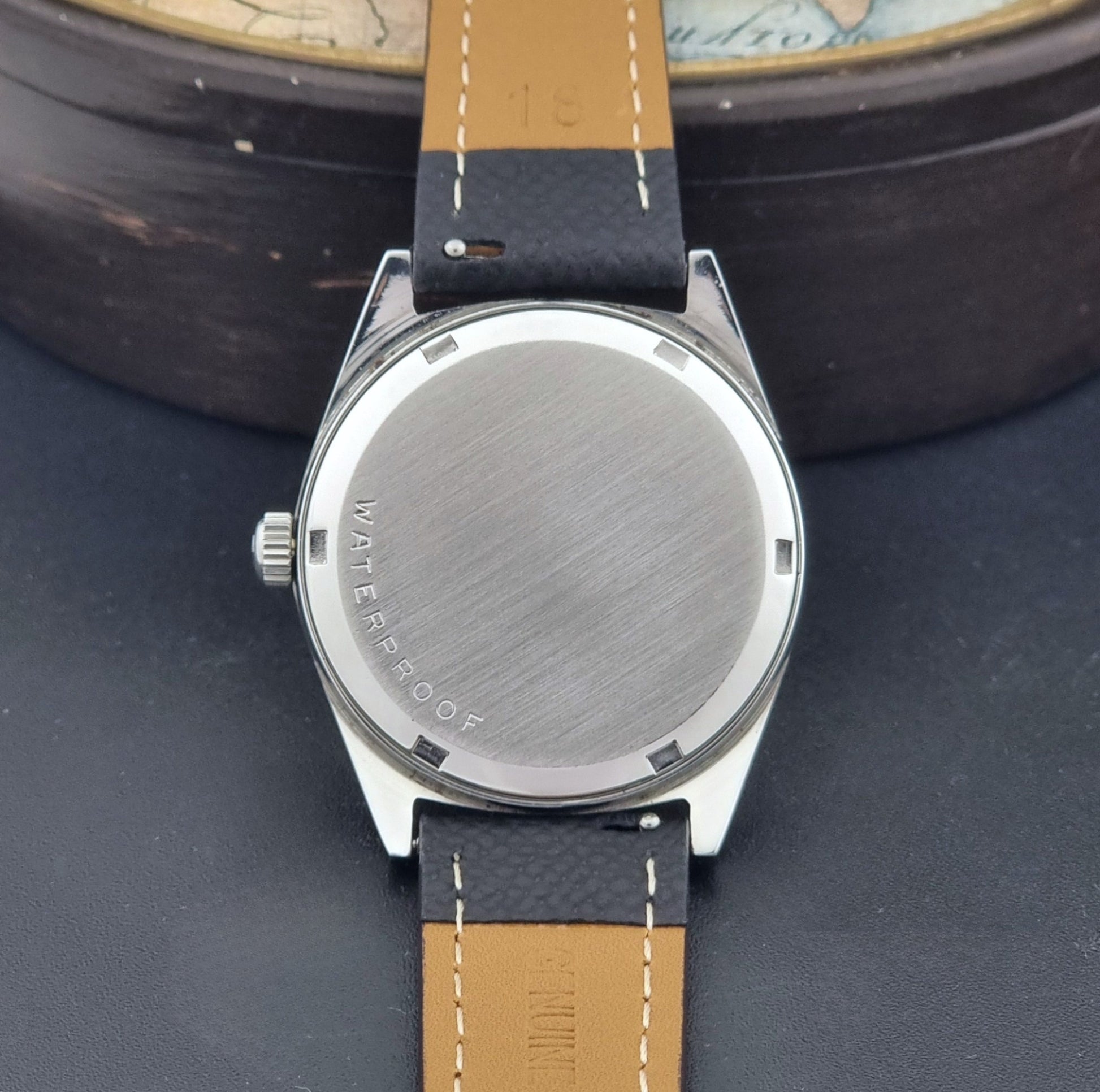 Vintage Omega Geneve 136.041 watch with black strap on a dark background case back view