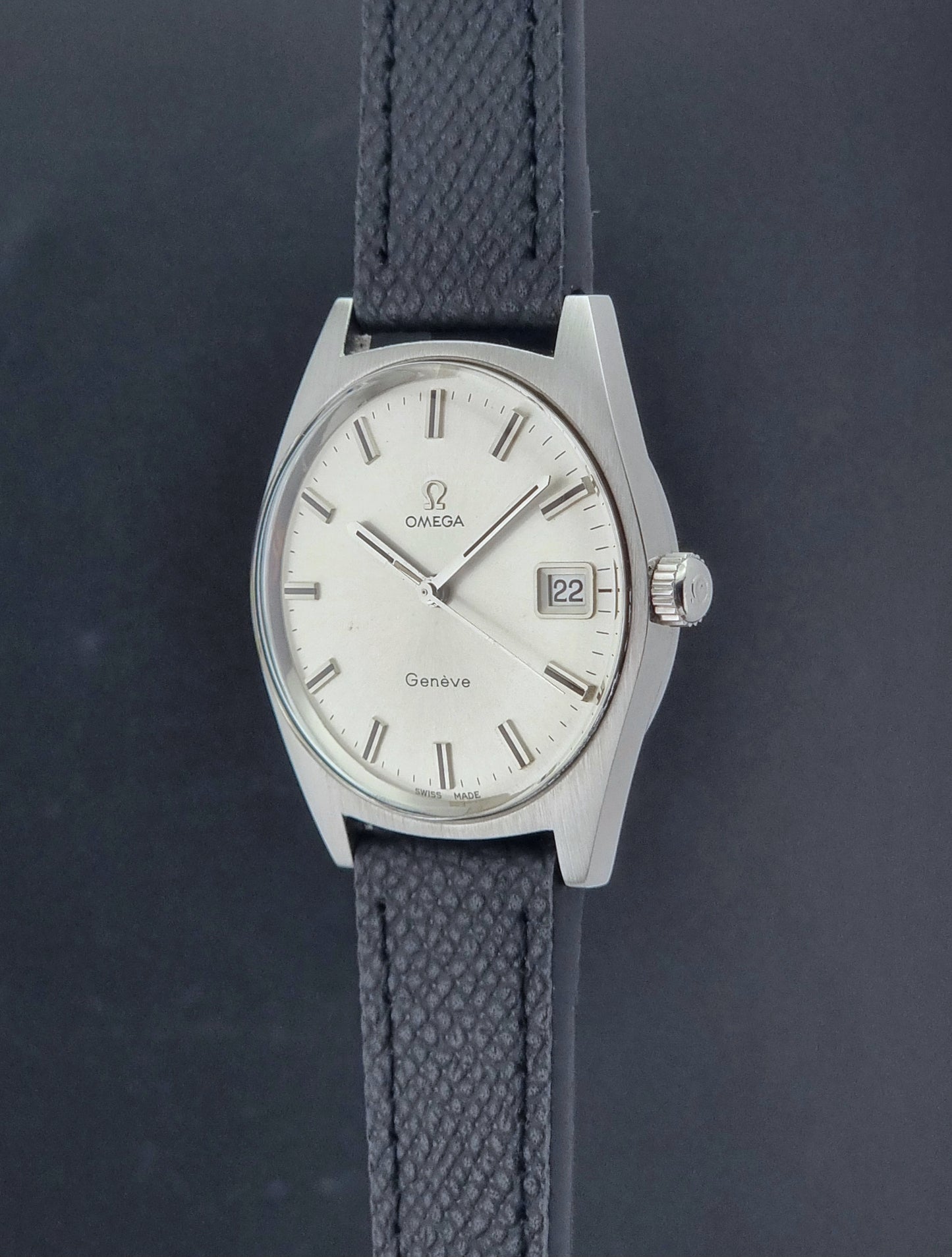 Vintage Omega Geneve 136.041 watch with black strap on a dark background crown profile view