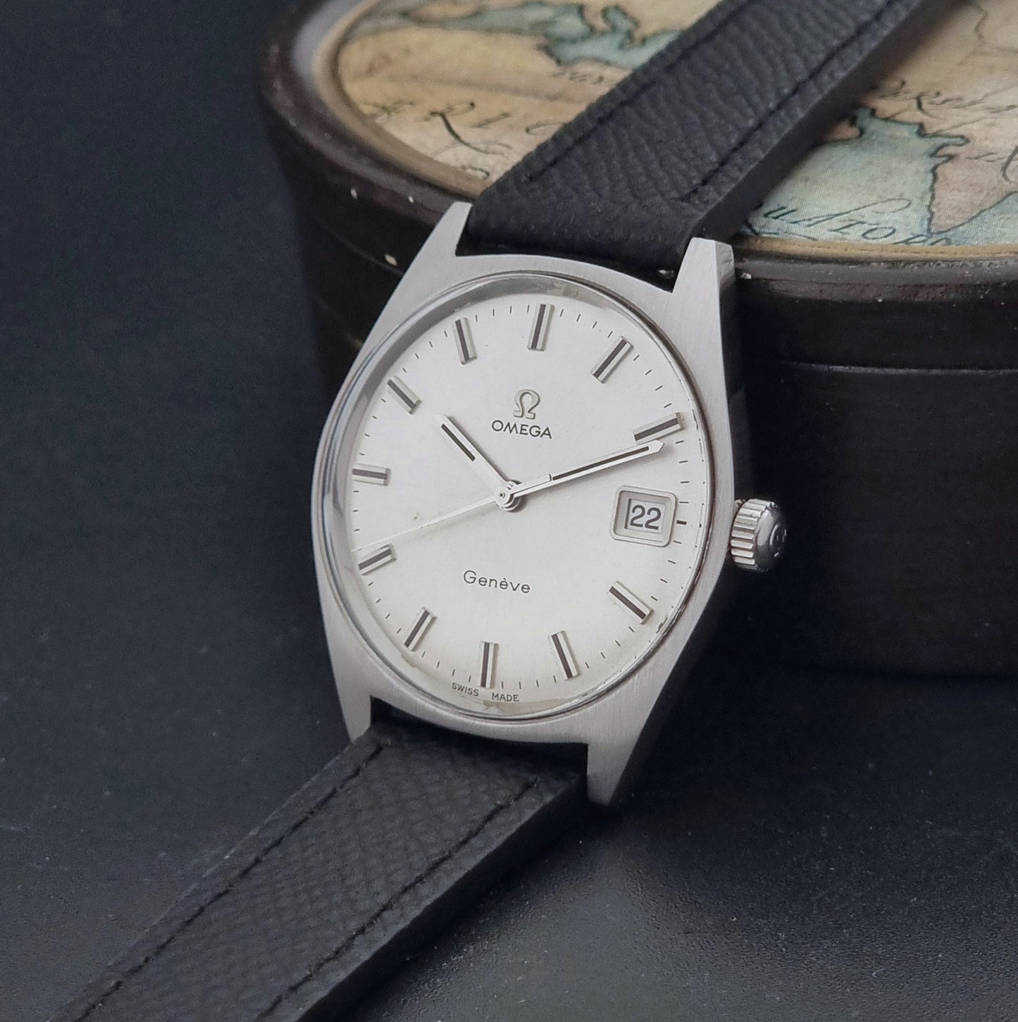 Vintage Omega Geneve 136.041 watch with black strap on a dark background crown view