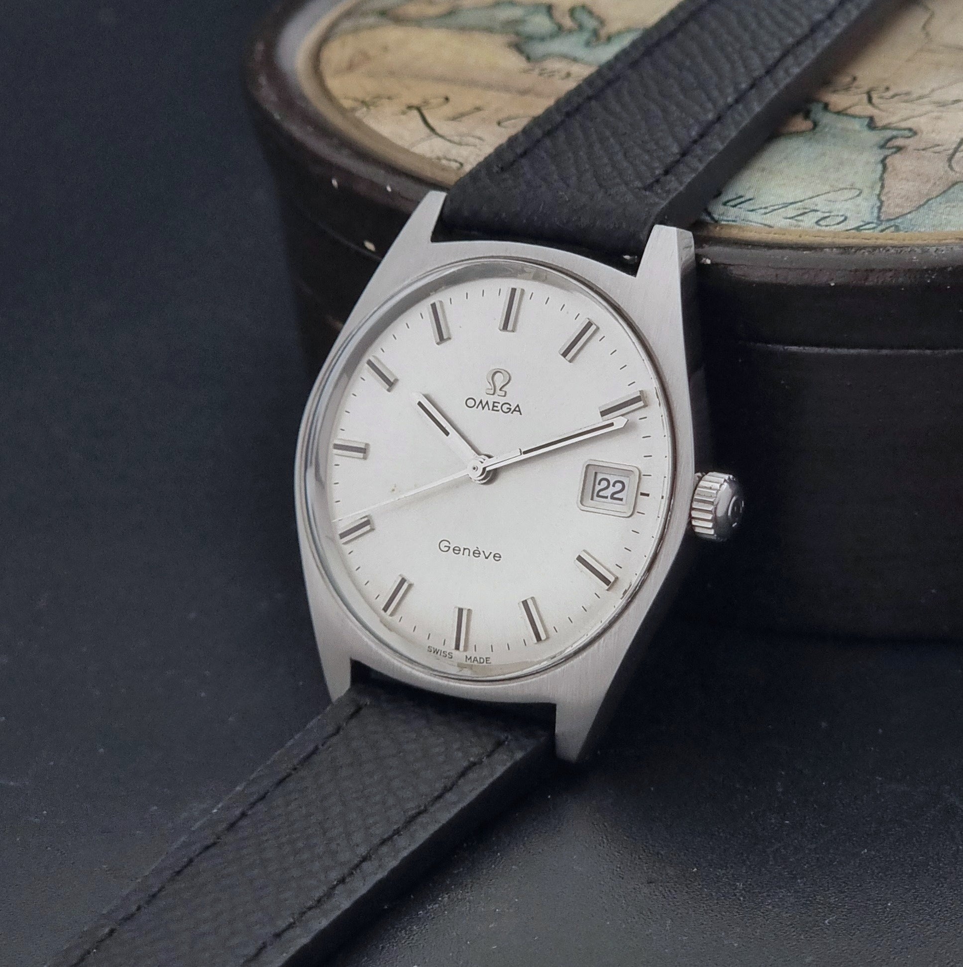 Vintage Omega Geneve 136.041 watch with black strap on a dark background crown view