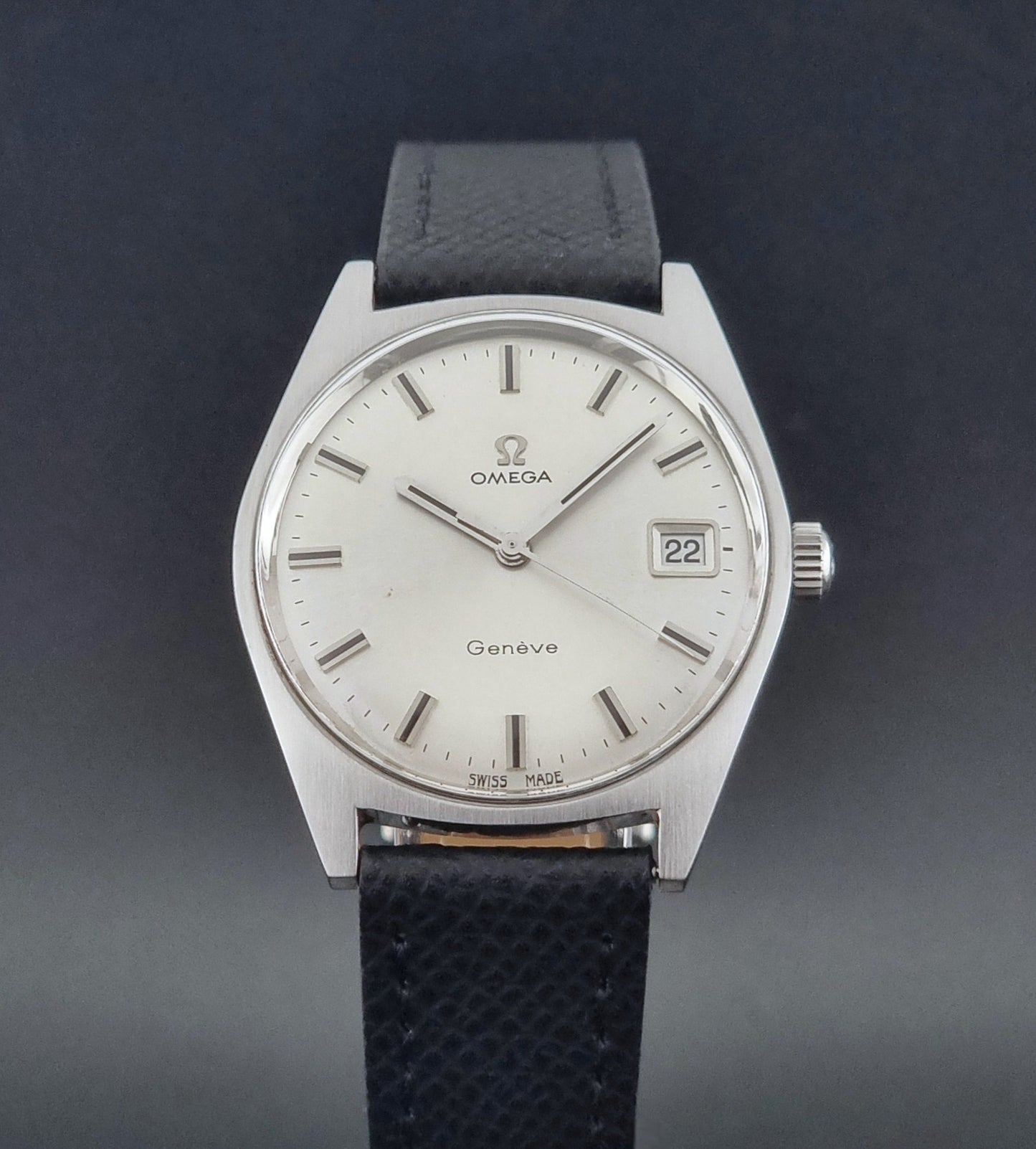Vintage Omega Geneve 136.041 watch with black strap on a dark background close up dial view