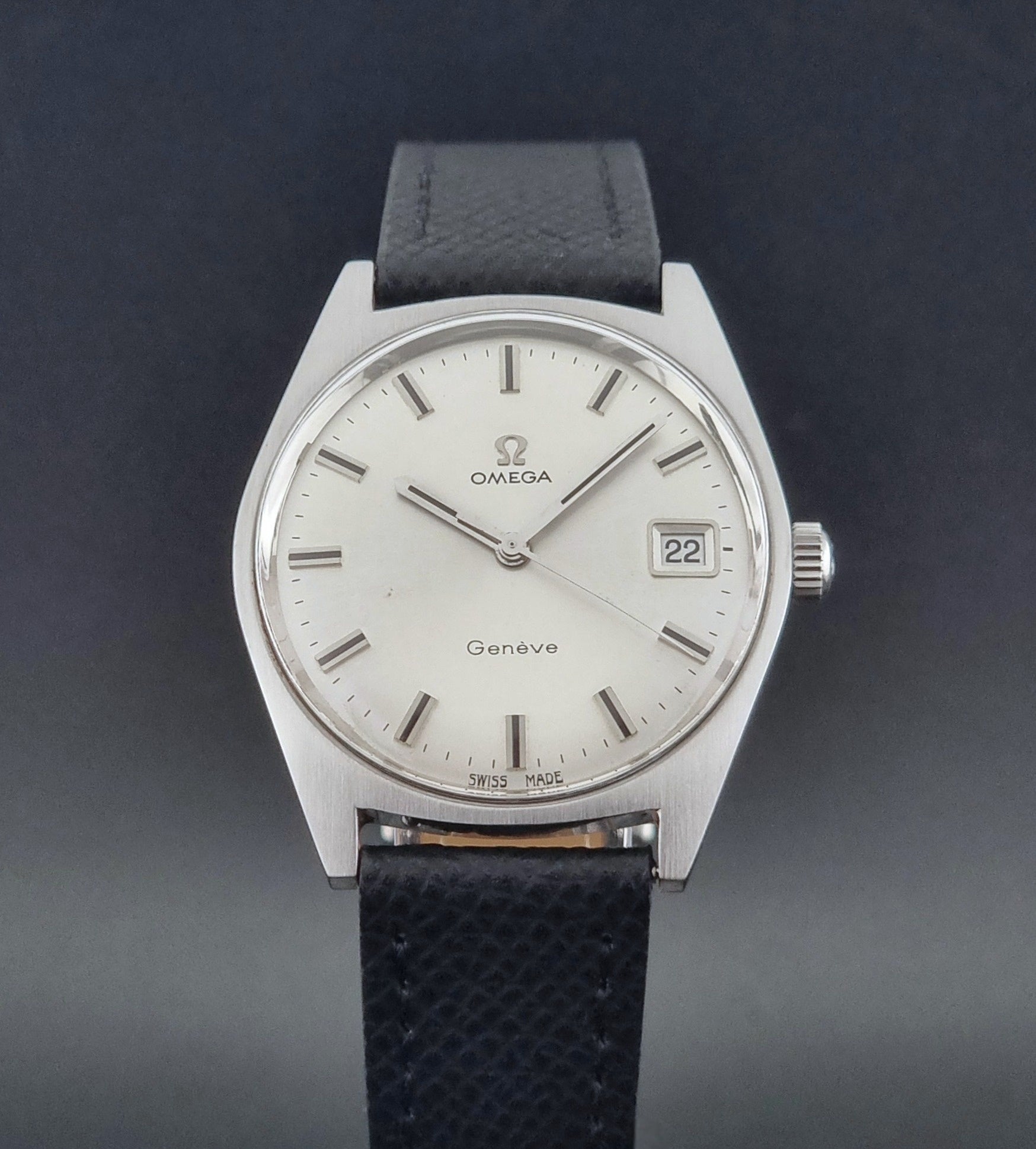 Vintage Omega Geneve 136.041 watch with black strap on a dark background close up dial view