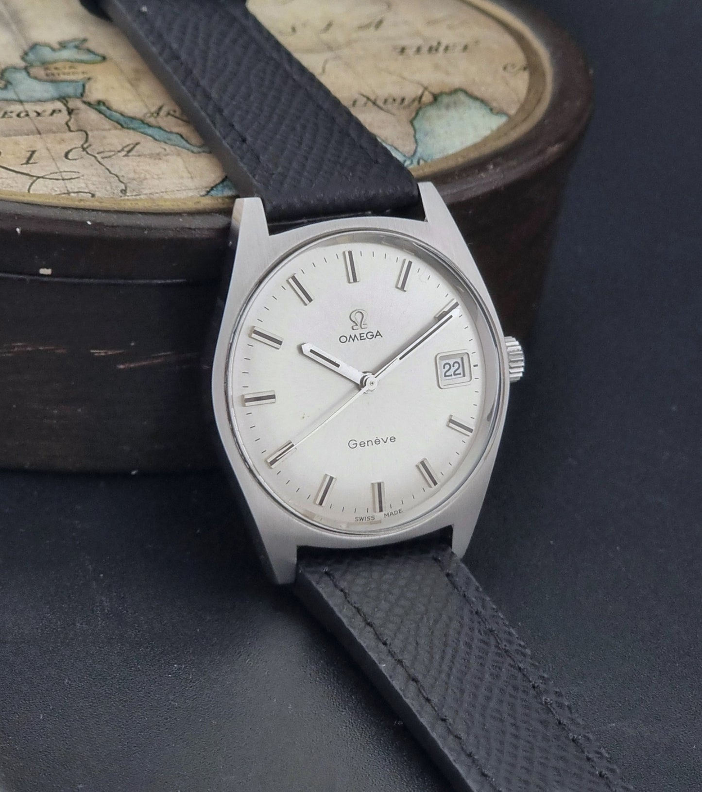 Vintage Omega Geneve 136.041 watch with black strap on a dark background side view