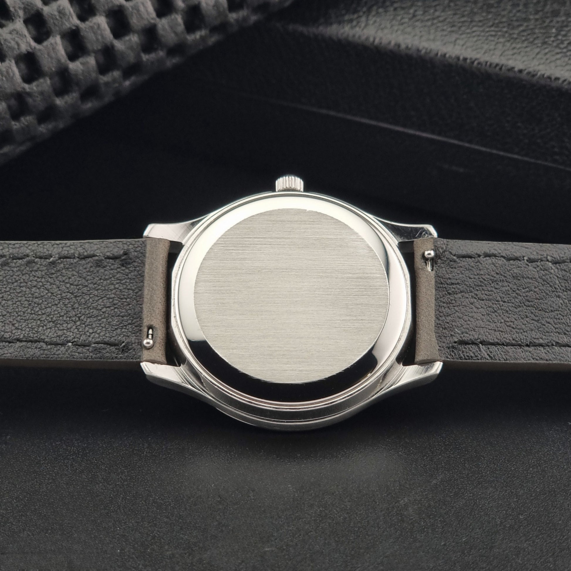 Vintage Omega Quartz Wristwatch 196.0071 with a grey strap on a dark background back view