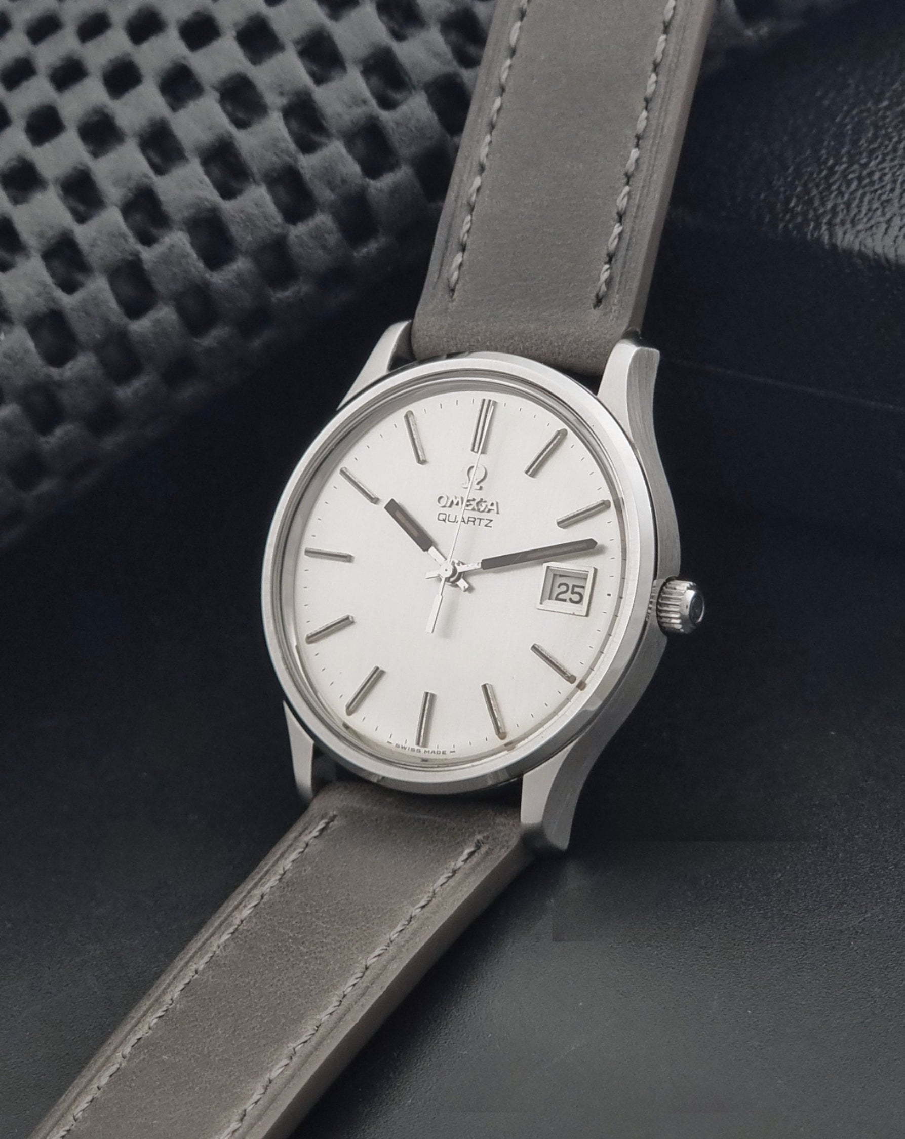 Vintage Omega Quartz Wristwatch 196.0071 with a grey strap on a dark background crown view