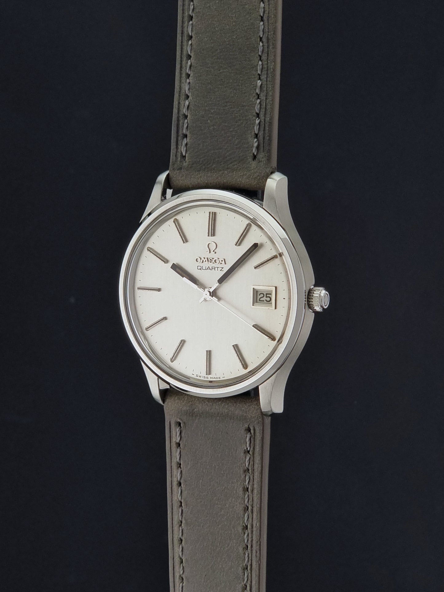 Vintage Omega Quartz Wristwatch 196.0071 with a grey strap on a dark background crown profile view