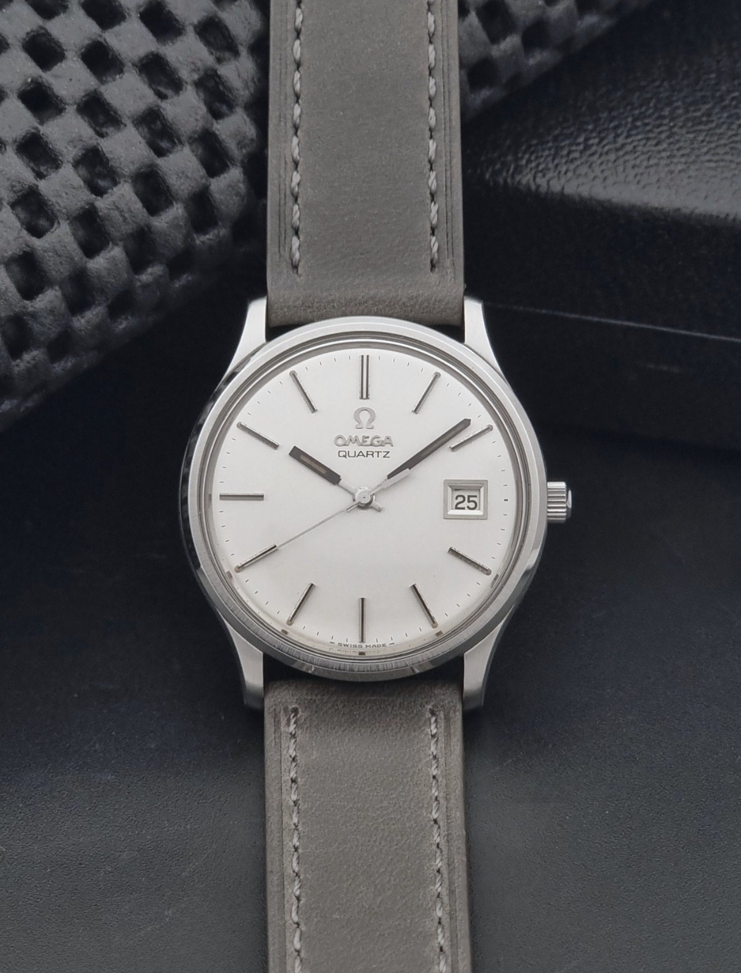 Vintage Omega Quartz Wristwatch 196.0071 with a grey strap on a dark background dial view