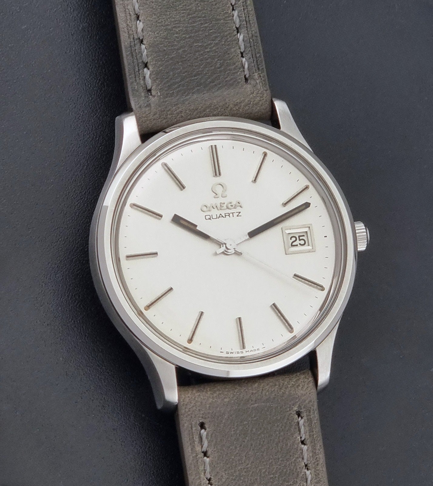 Vintage Omega Quartz Wristwatch 196.0071 with a grey strap on a dark background front view