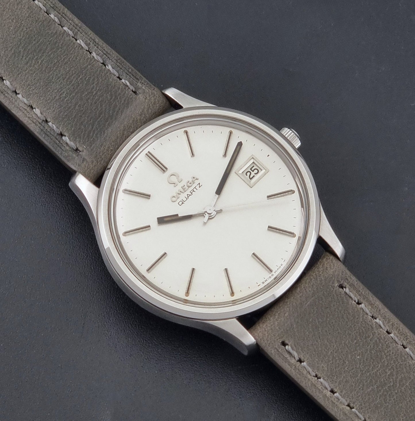 Vintage Omega Quartz Wristwatch 196.0071 with a grey strap on a dark background close up dial view