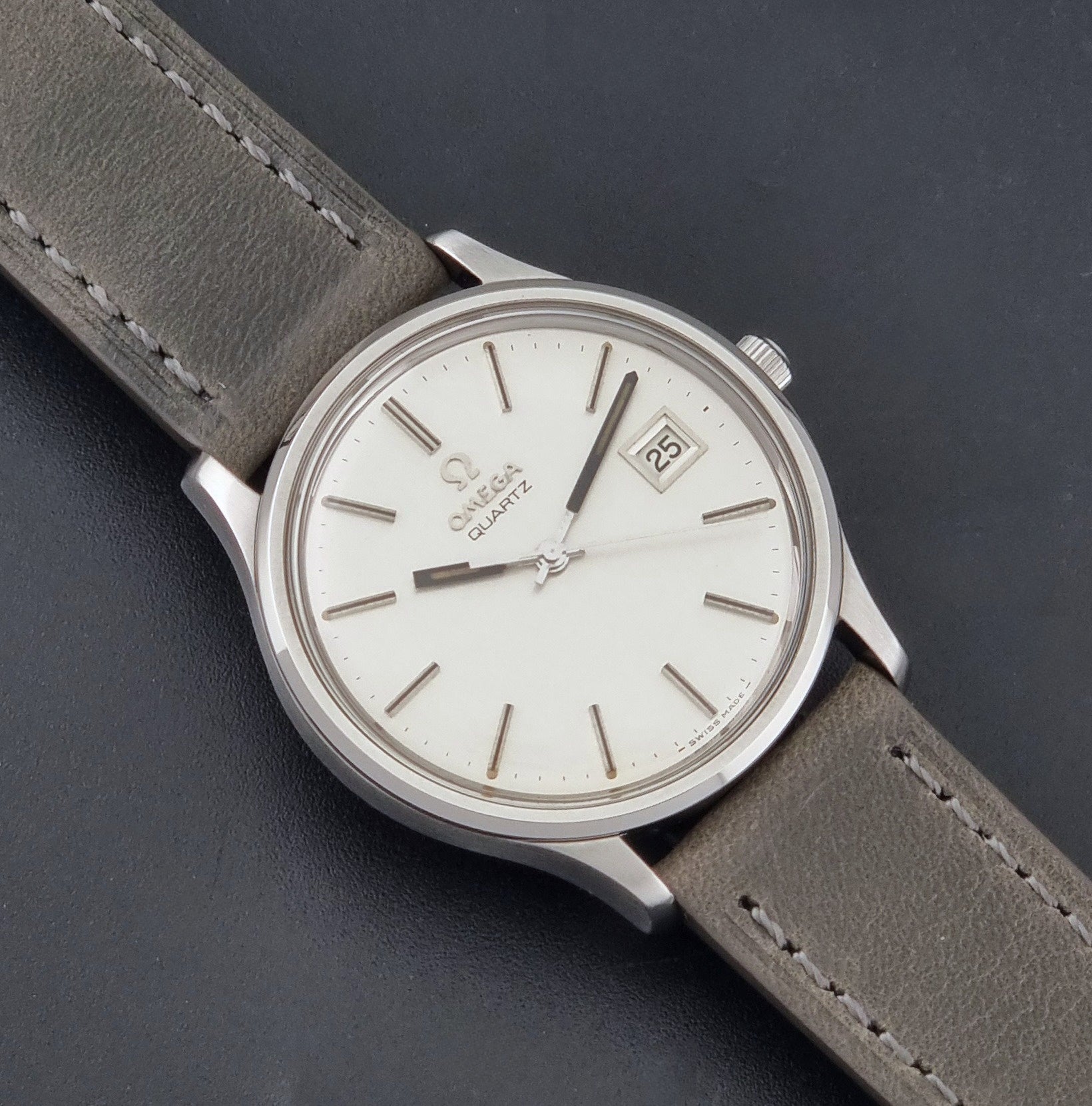 Vintage Omega Quartz Wristwatch 196.0071 with a grey strap on a dark background close up dial view