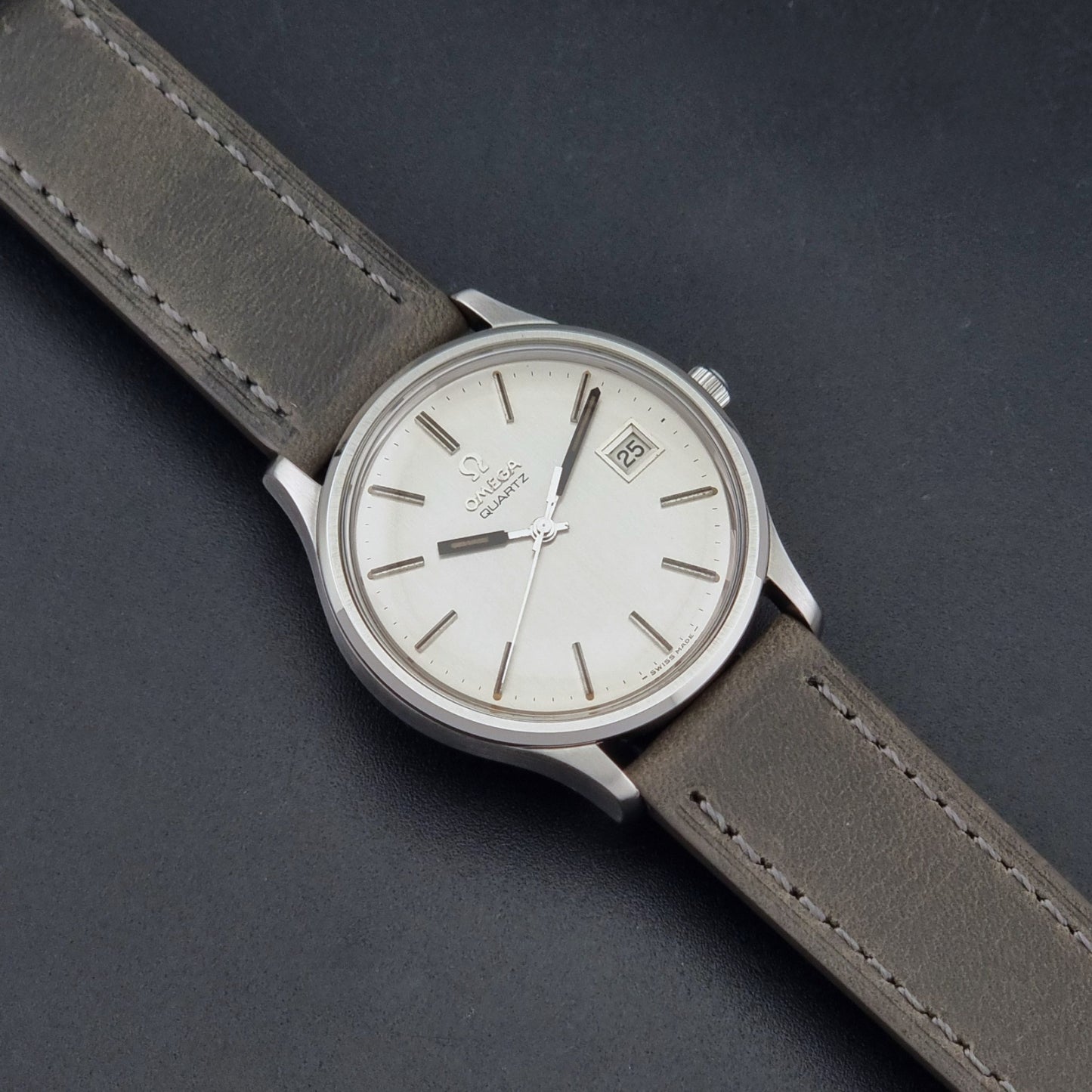 Vintage Omega Quartz Wristwatch 196.0071 with a grey strap on a dark background dial