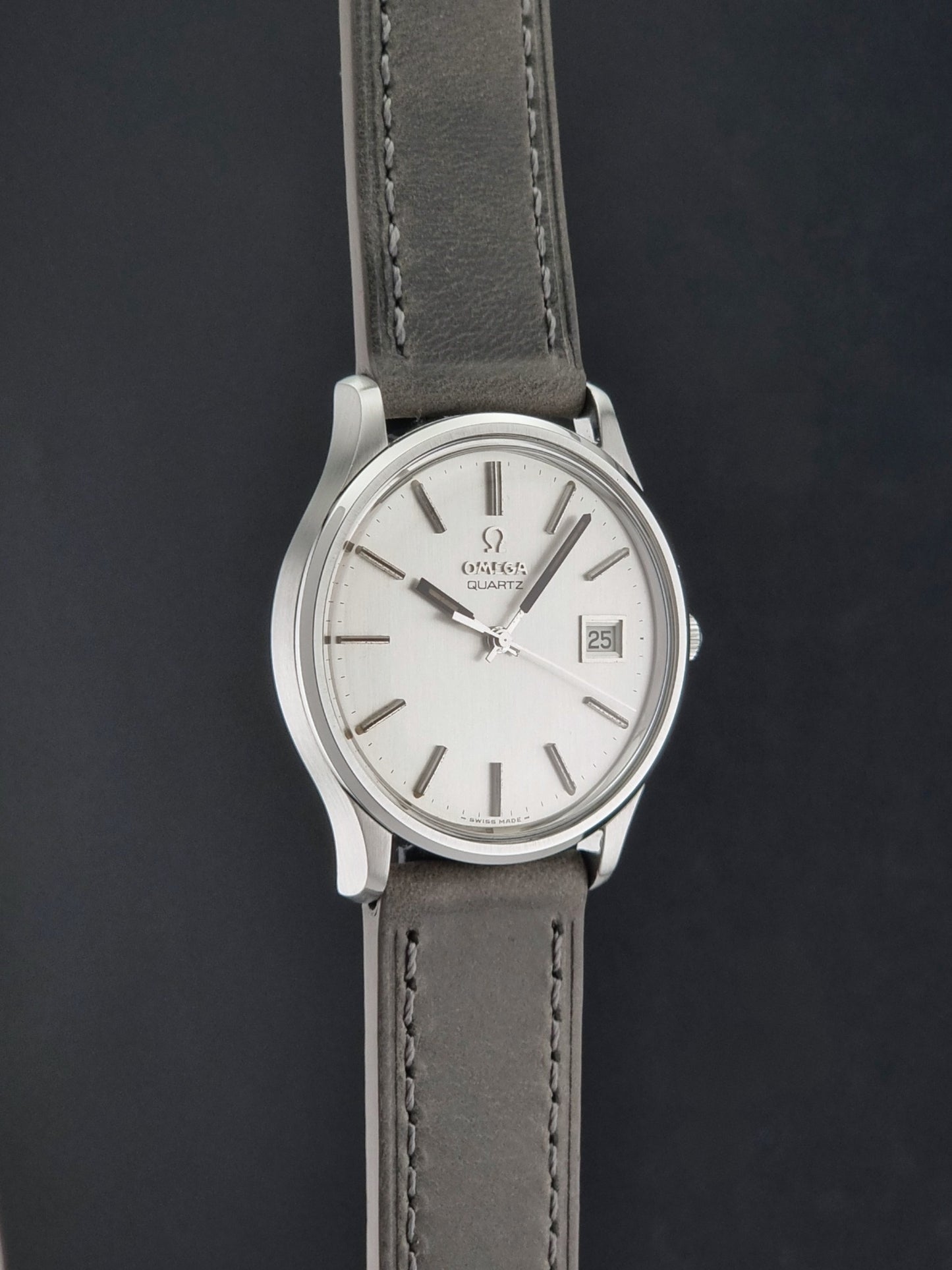 Vintage Omega Quartz Wristwatch 196.0071 with a grey strap on a dark background side profile view