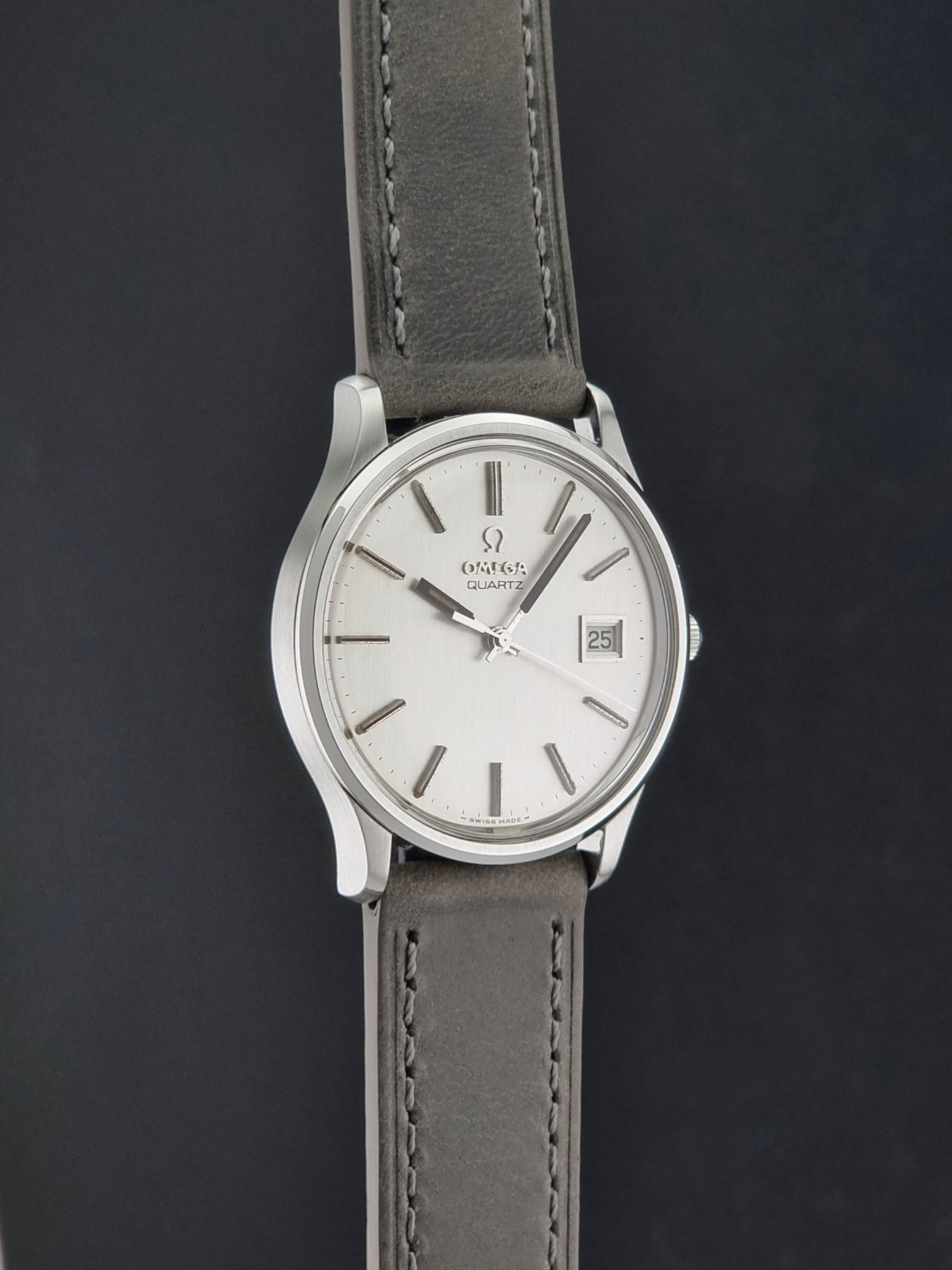 Vintage Omega Quartz Wristwatch 196.0071 with a grey strap on a dark background side profile view