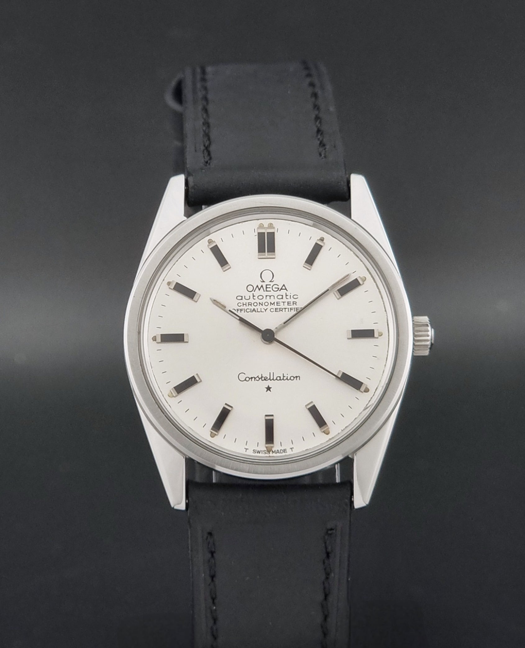 Vintage Omega Constellation 167.021 watch with a silver-toned case and black leather strap, on a dark background close dial view